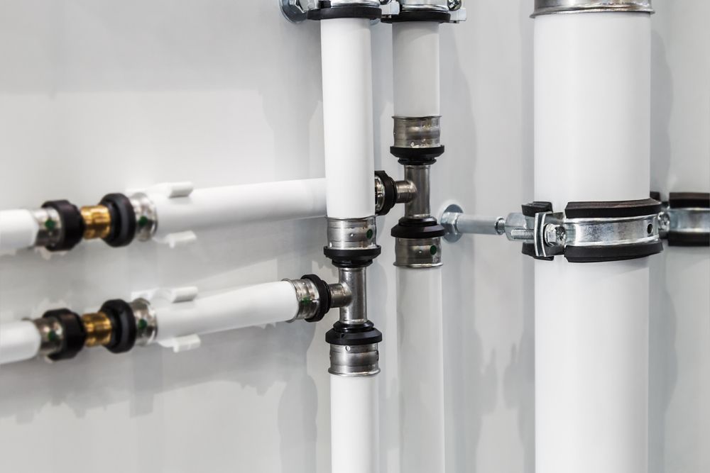 A Close Up of a Row of White Pipes Attached to a Wall — Gastech Plumbing Services in Sarina, QLD