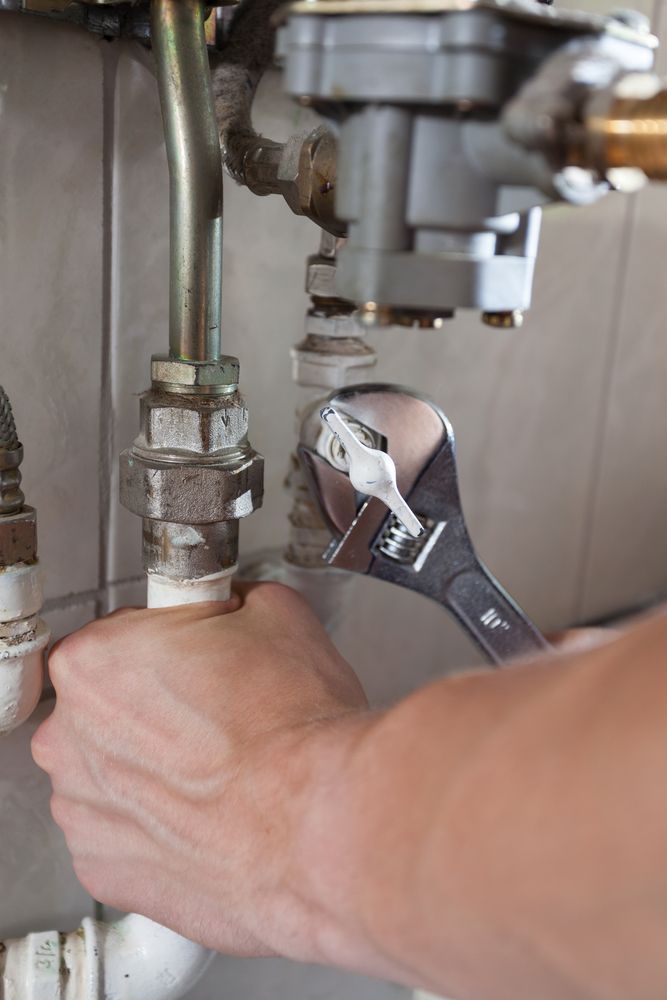 A Person is Fixing a Pipe With a Wrench — Gastech Plumbing Services in Andergrove, QLD