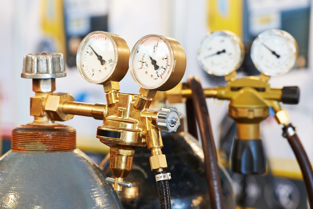 A Row of Gas Cylinders With Gauges Attached to Them — Gastech Plumbing Services in Marian, QLD