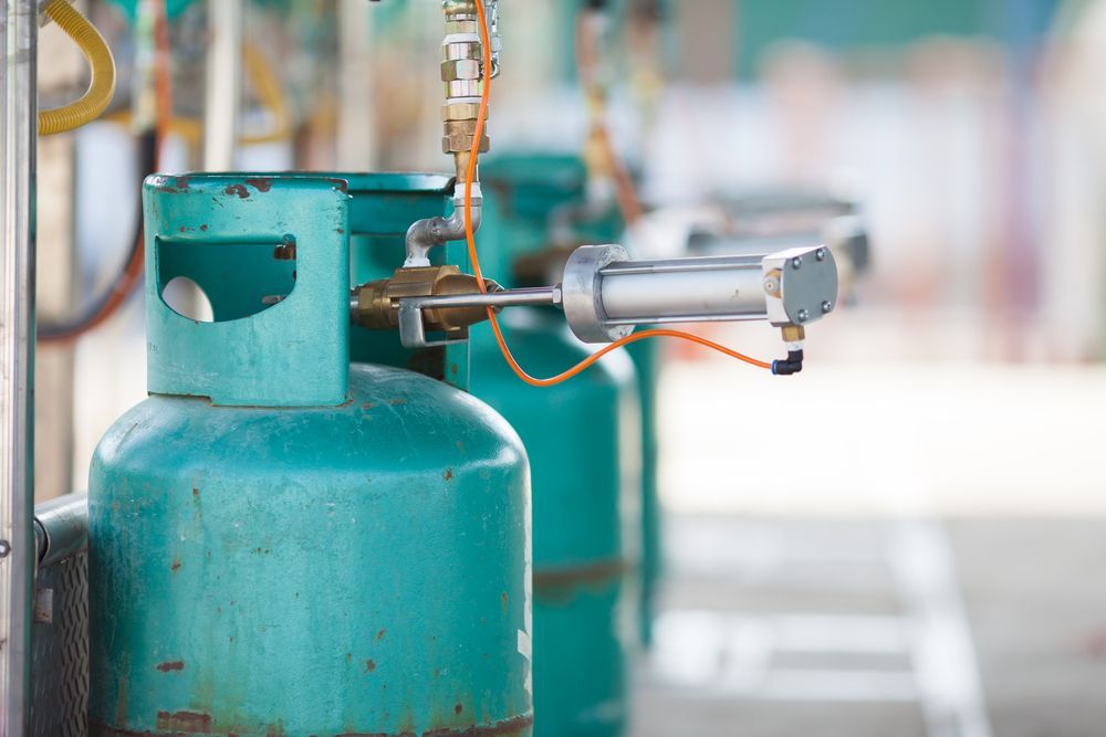 A Row of Gas Cylinders Sitting Next to Each Other in a Gas Station — Gastech Plumbing Services in Andergrove, QLD