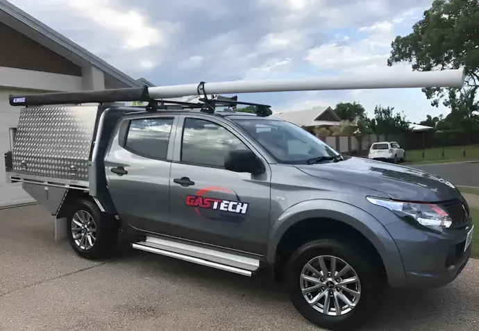 A Gray Truck With a White Pipe on the Roof is Parked in Front of a House — Gastech Plumbing Services in Andergrove, QLD