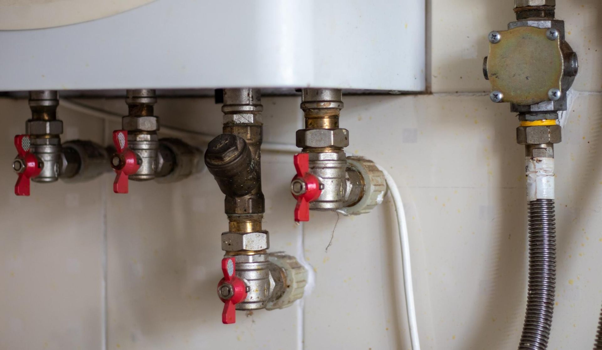 A Close Up of a Water Heater With Red Valves — Gastech Plumbing Services in Sarina, QLD