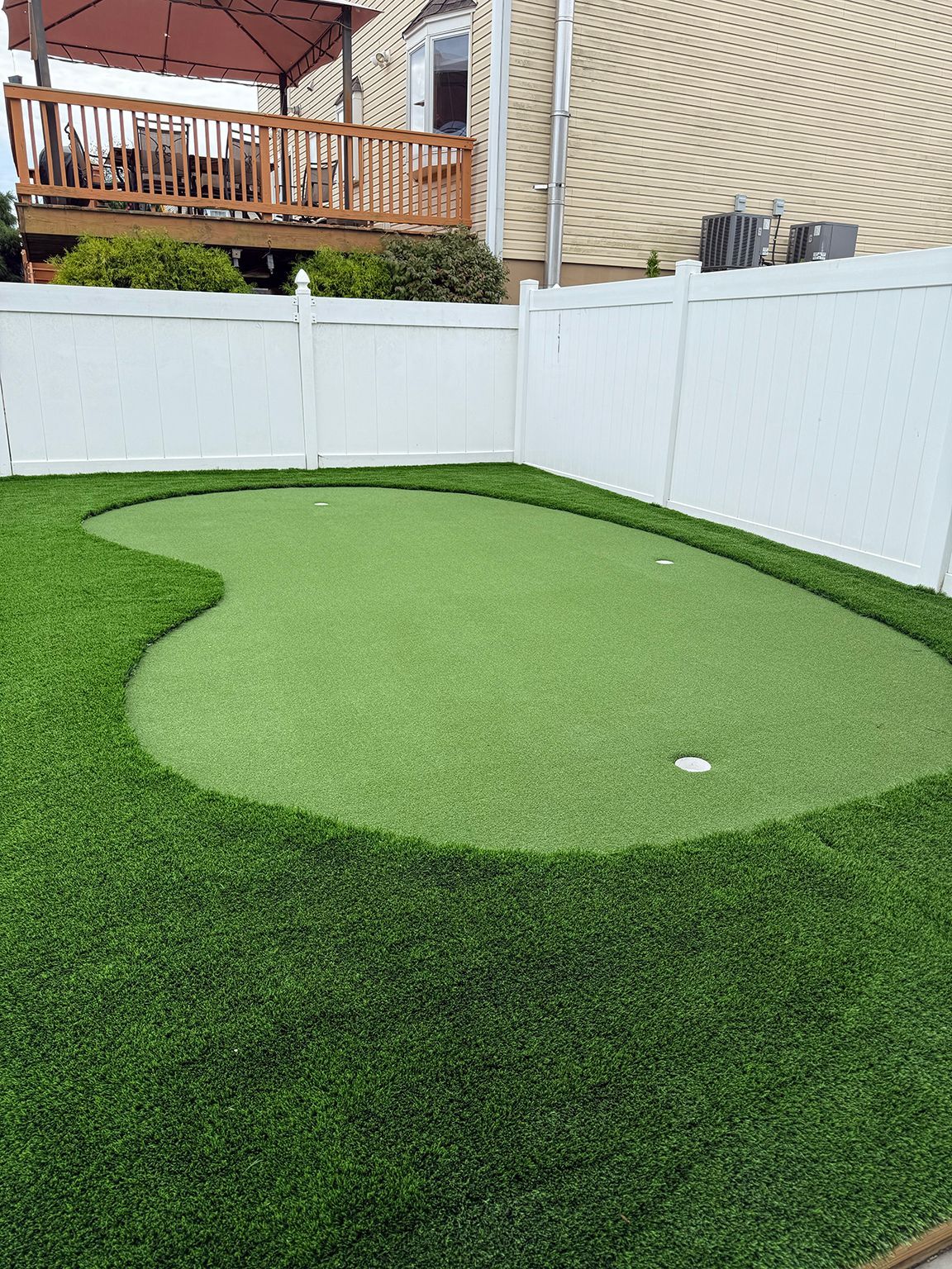 Artificial turf backyard with fenced landscape and deck
