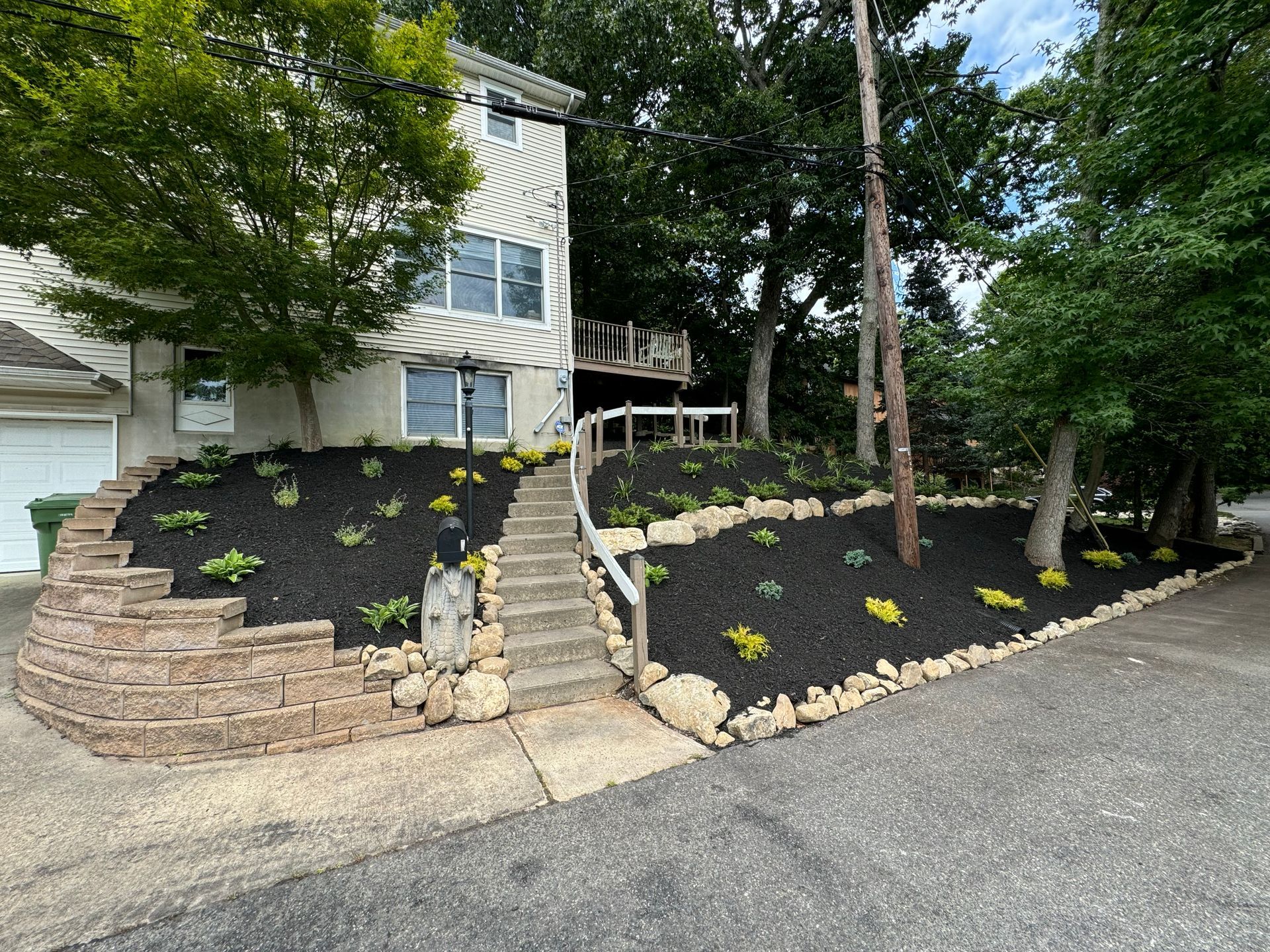 Retaining wall with stone steps and newly planted landscape beds