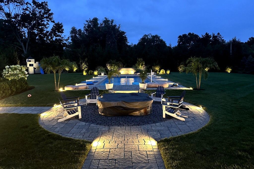 Outdoor landscape lighting illuminating patio and seating area at night