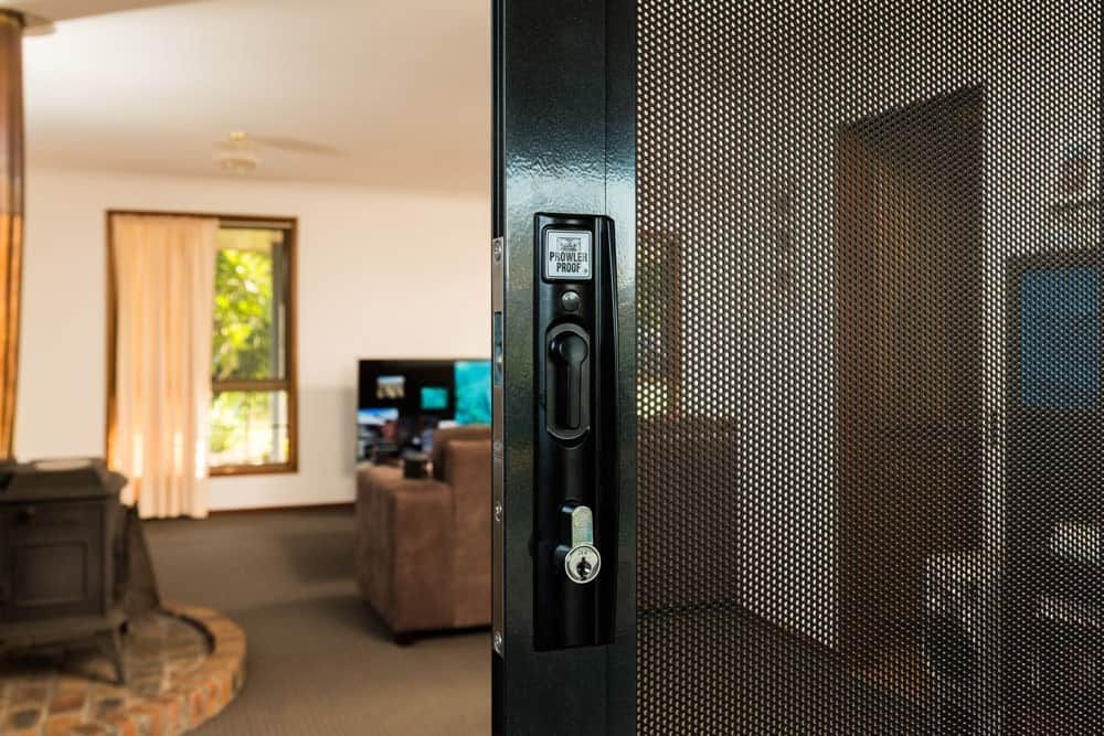 Person Using a Screwdriver to Install or Repair a Door Lock — All Security Screens & Repairs In Bungalow, QLD