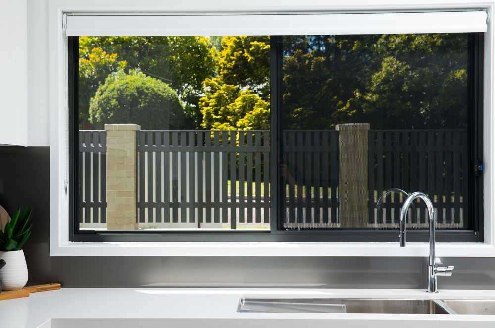 Hand Opening a Dark Framed Window, With a View of Greenery — All Security Screens & Repairs In Bungalow, QLD