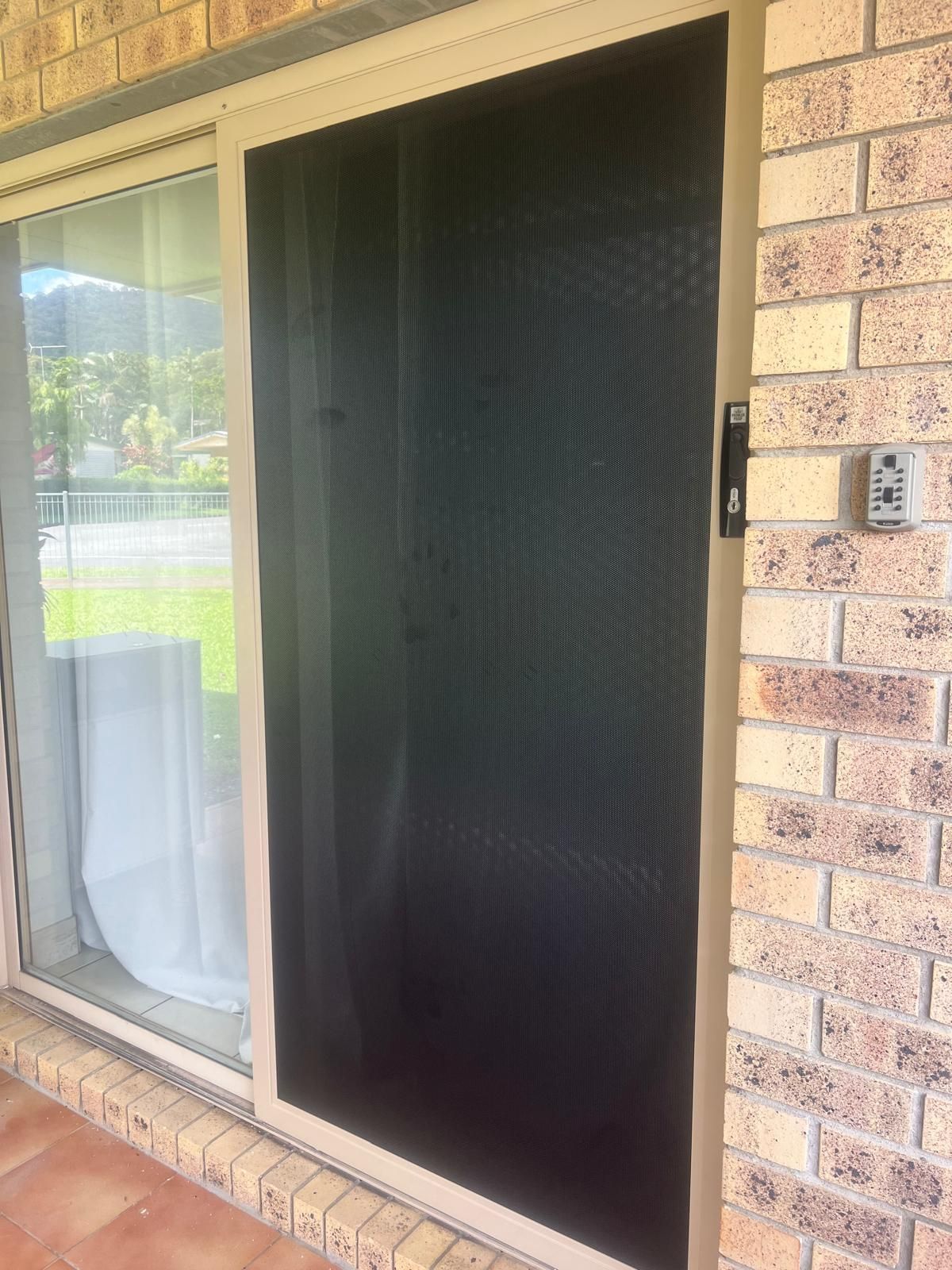 Tan Screen Door on a Brick Wall Next to a Sliding Glass Door — All Security Screens & Repairs In Bungalow, QLD