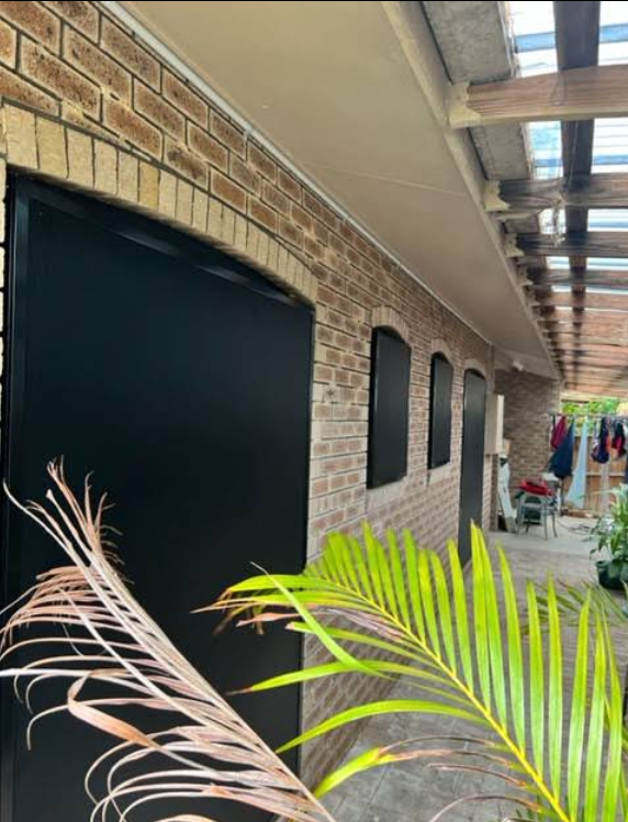 Hand Turning a Window Handle; Exterior View of Trees and House — All Security Screens & Repairs In Bungalow, QLD