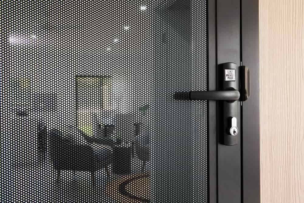 Person Installing a New Door Lock Cylinder With a Key, Silver and White — All Security Screens & Repairs In Bungalow, QLD