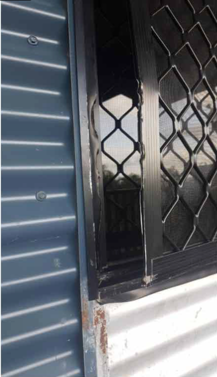 Window With Black Security Grill Beside Corrugated Metal Siding — All Security Screens & Repairs In Bungalow, QLD