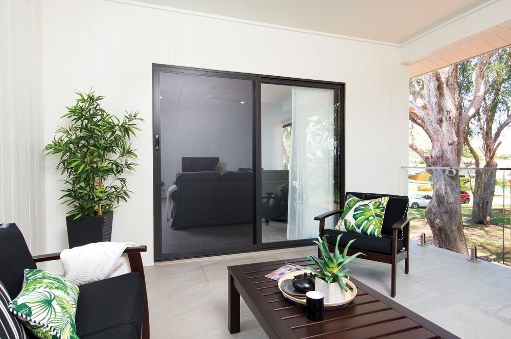 Patio With Black Furniture, Sliding Door, Potted Plant, and View of Trees — All Security Screens & Repairs In Bungalow, QLD
