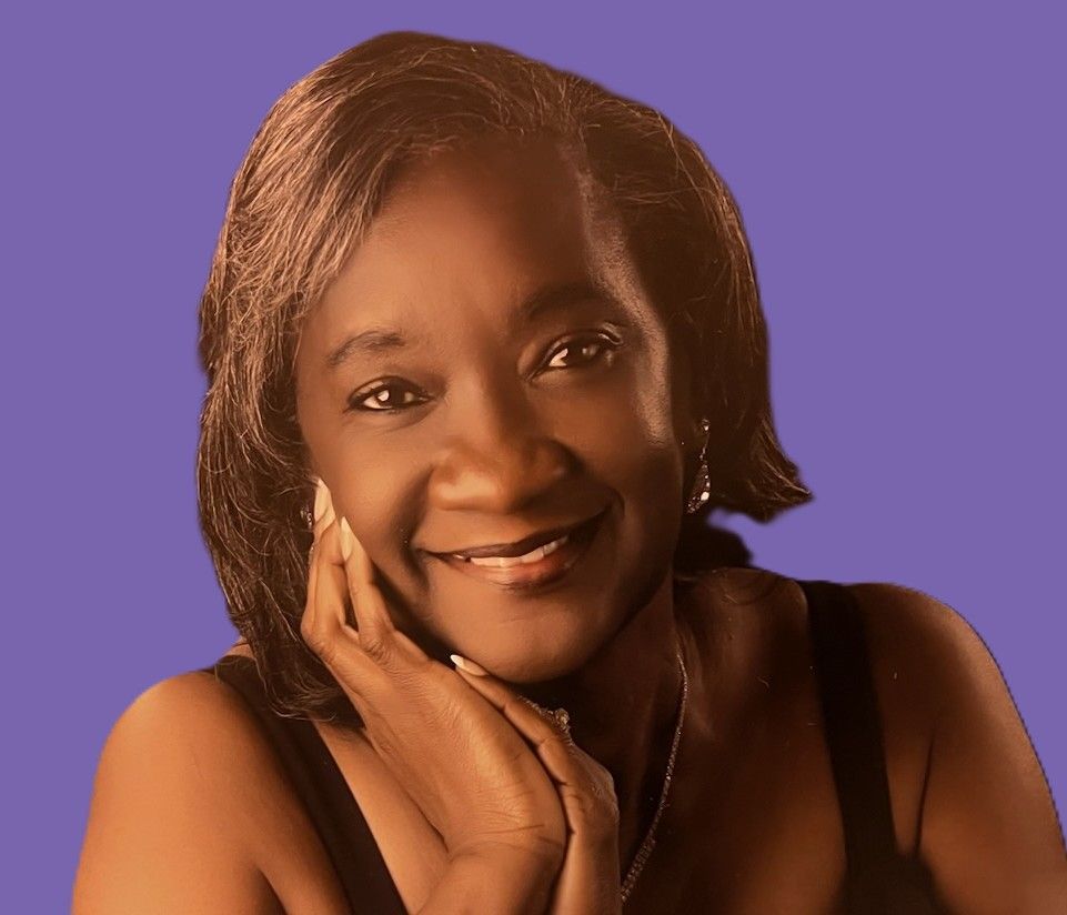 A woman is smiling with her hand on her chin