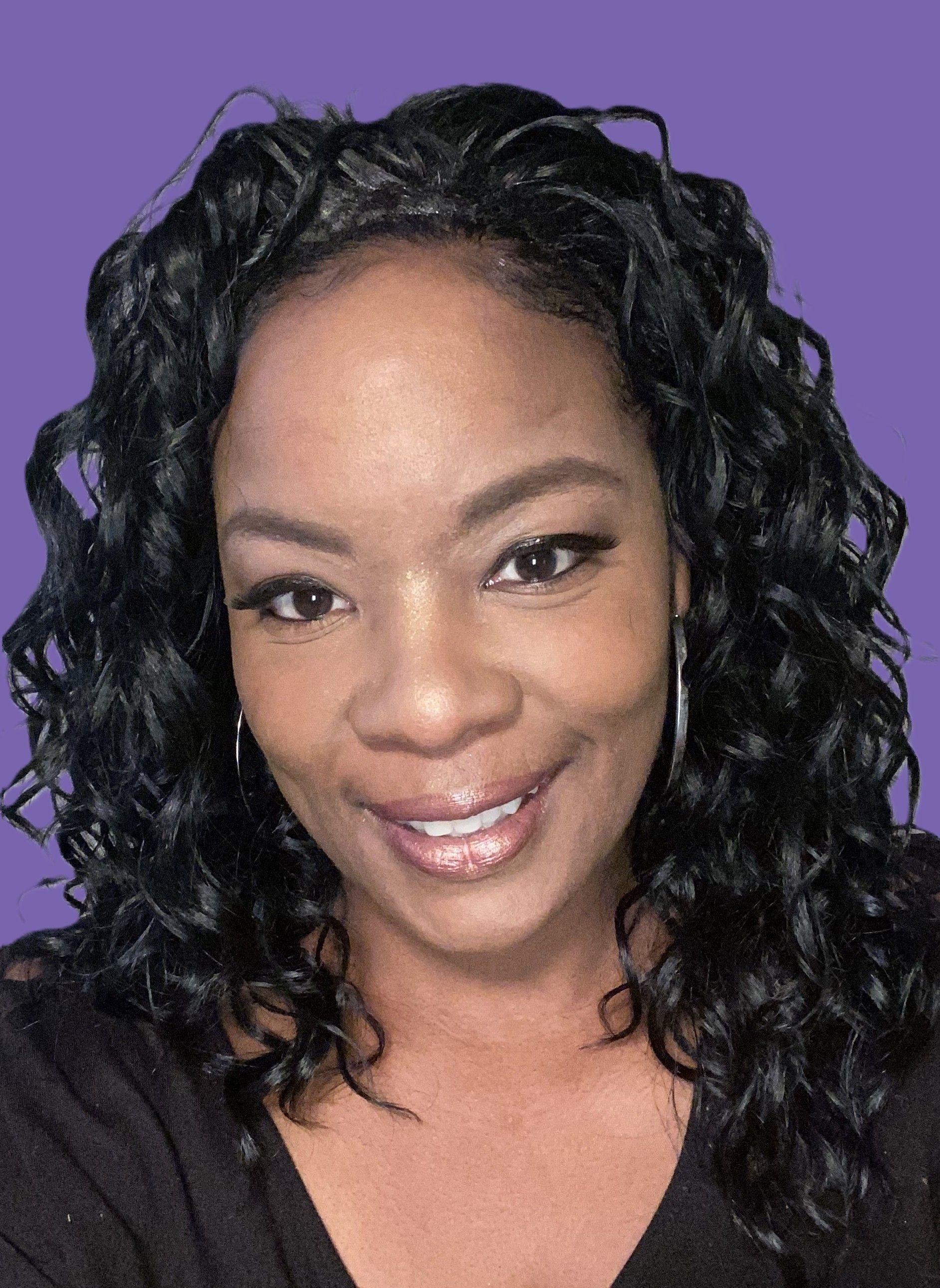 A woman with curly hair is smiling and wearing a black shirt.