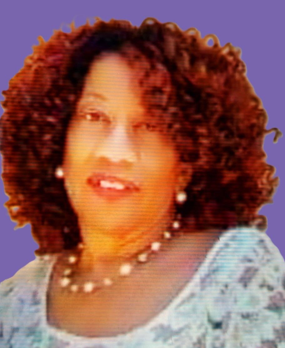 A woman with curly hair is wearing a necklace and earrings.