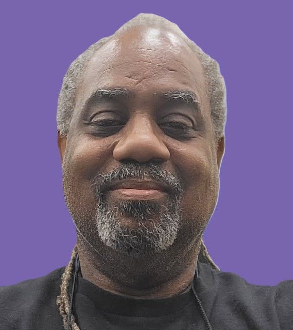 A man with a beard is smiling for the camera on a purple background.