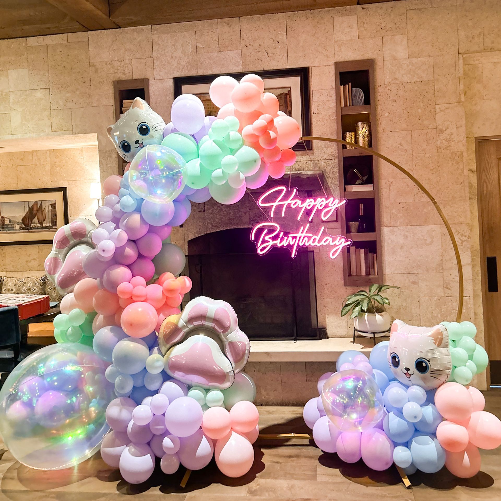 A room decorated with balloons and a neon sign that says happy birthday