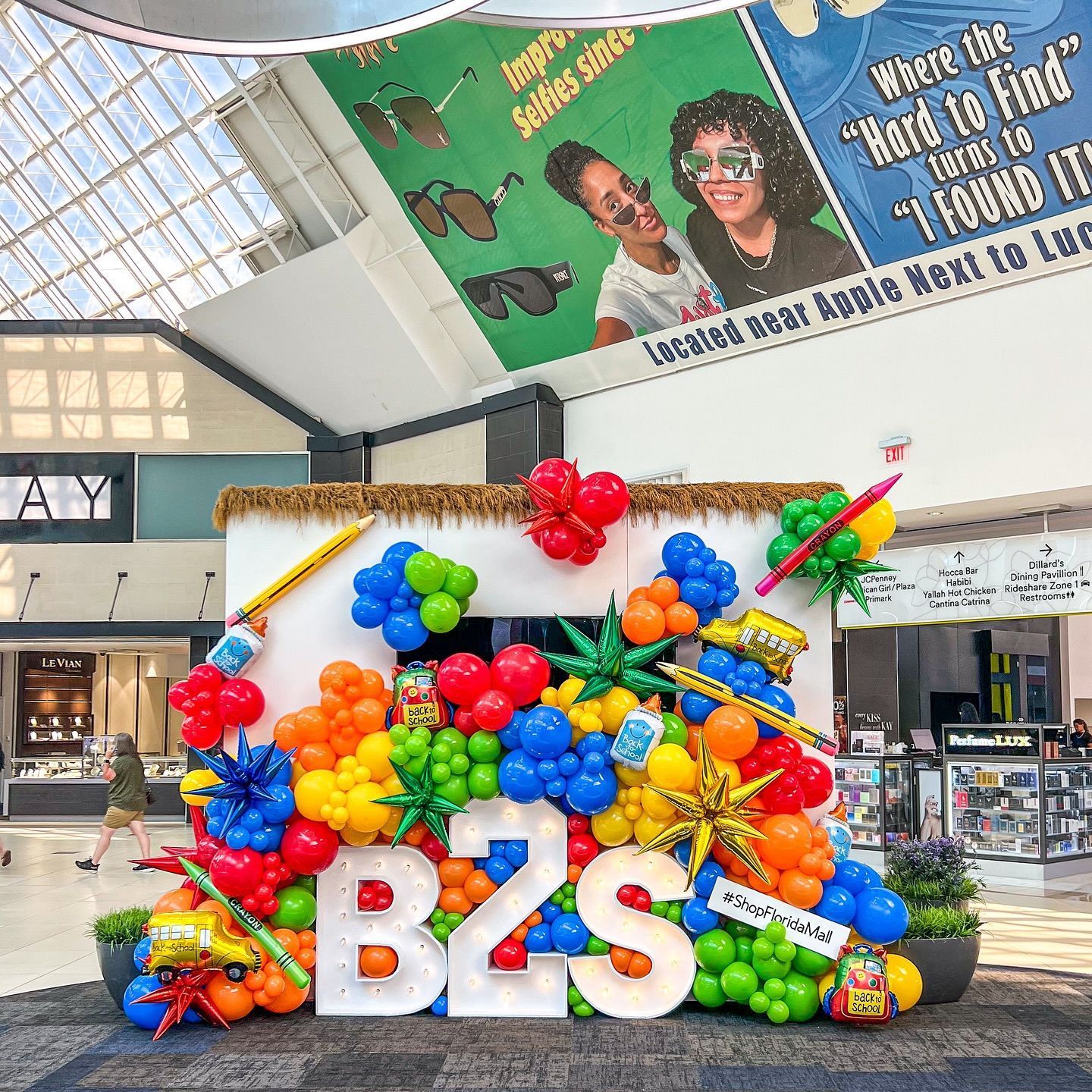 Colorful B2S (Back to School) balloon display in a mall, with decorations, and a sign.