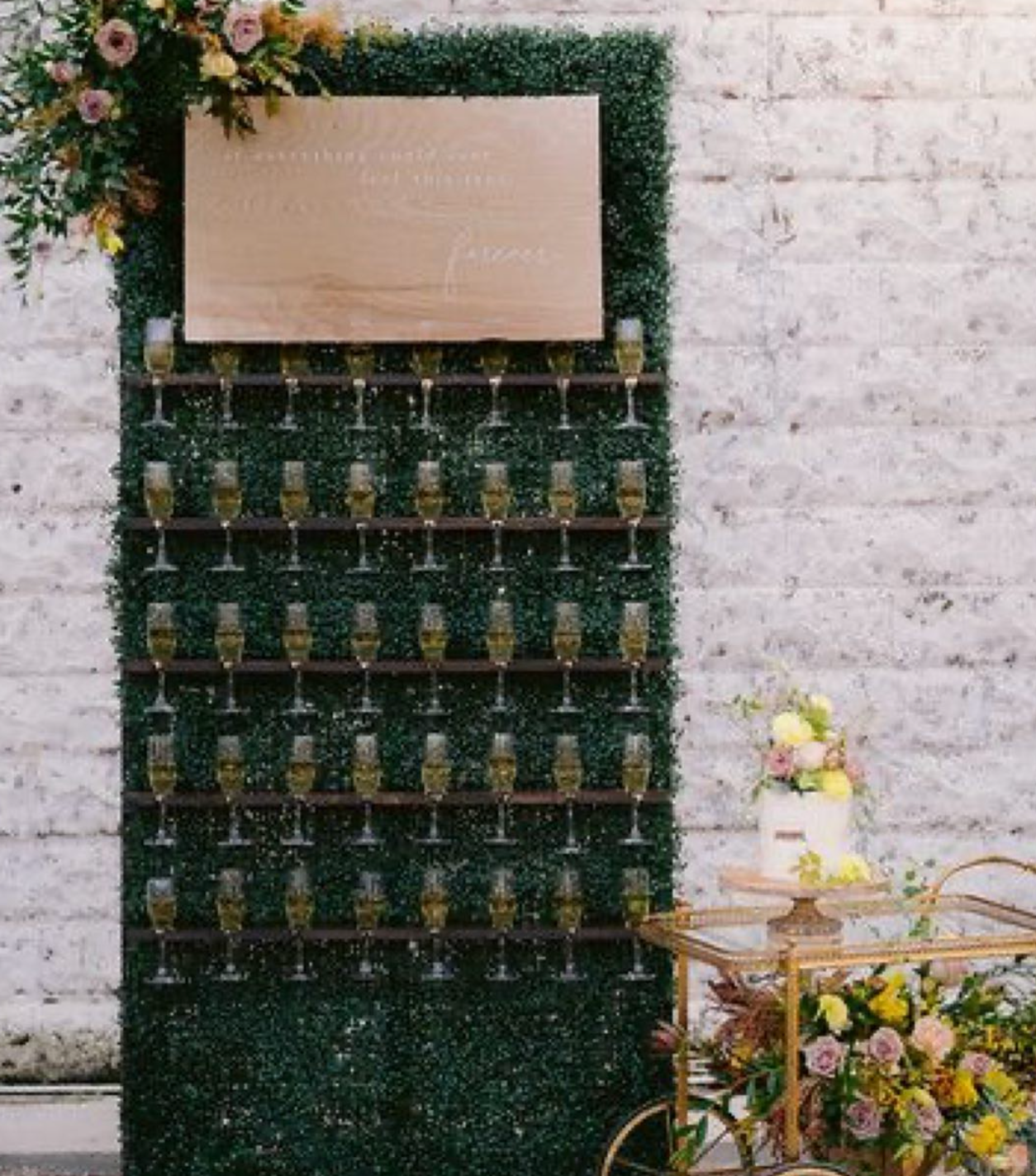 A wall filled with wine glasses and a cake on a table.