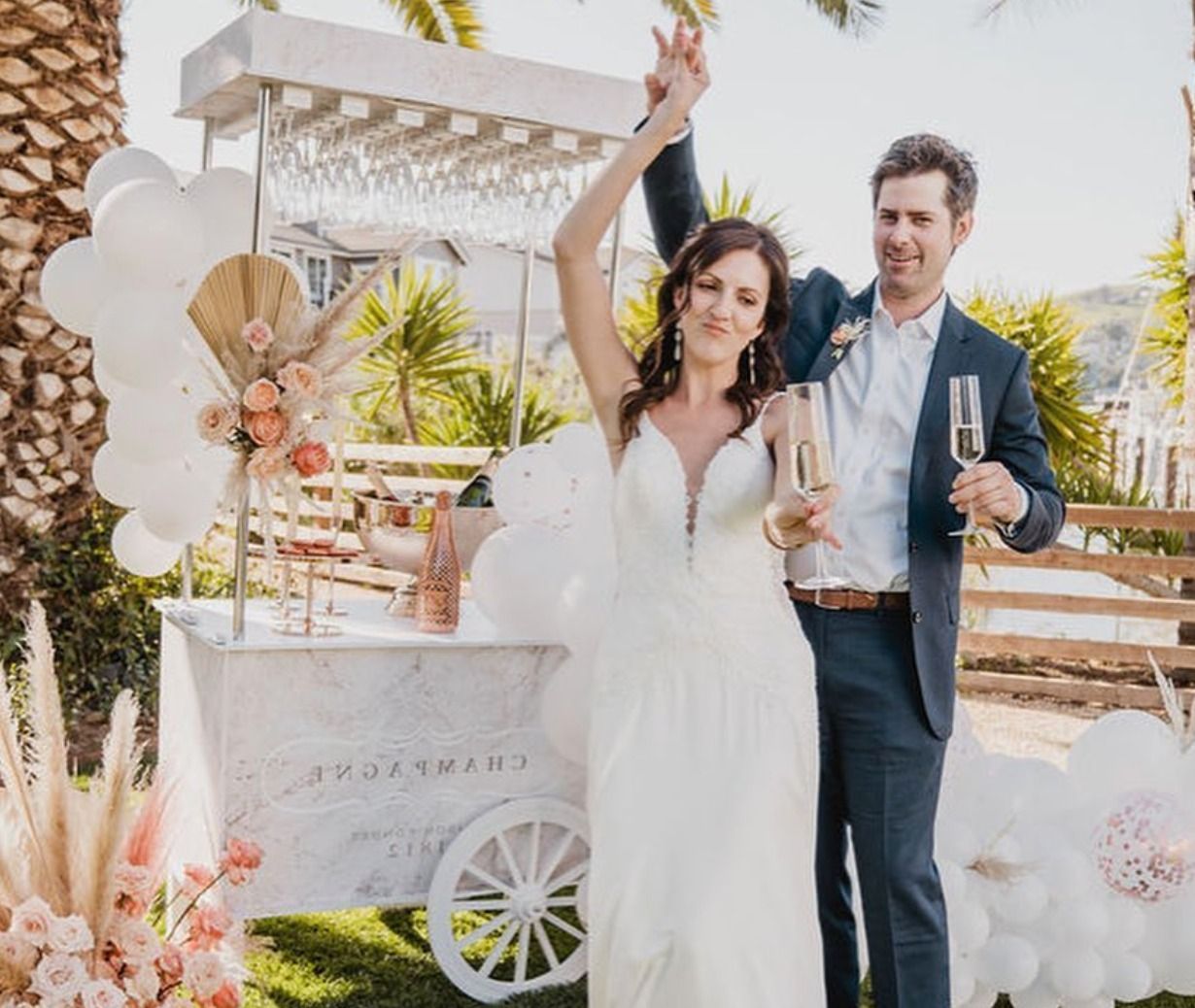 a bride and groom are holding champagne glasses in front of a cart .