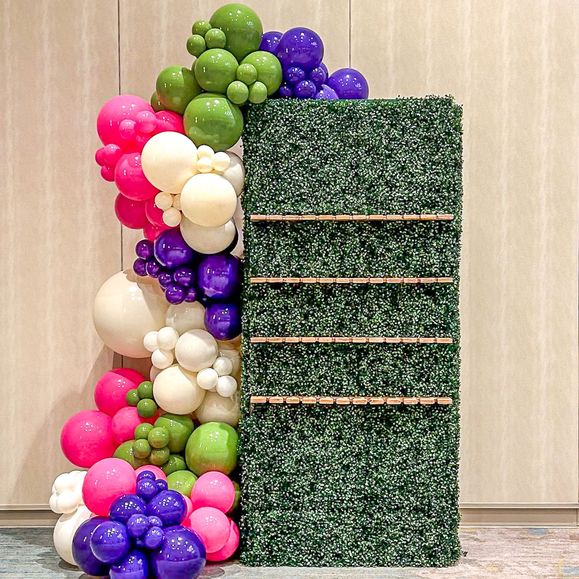 A wall filled with wine glasses and a cake on a table.