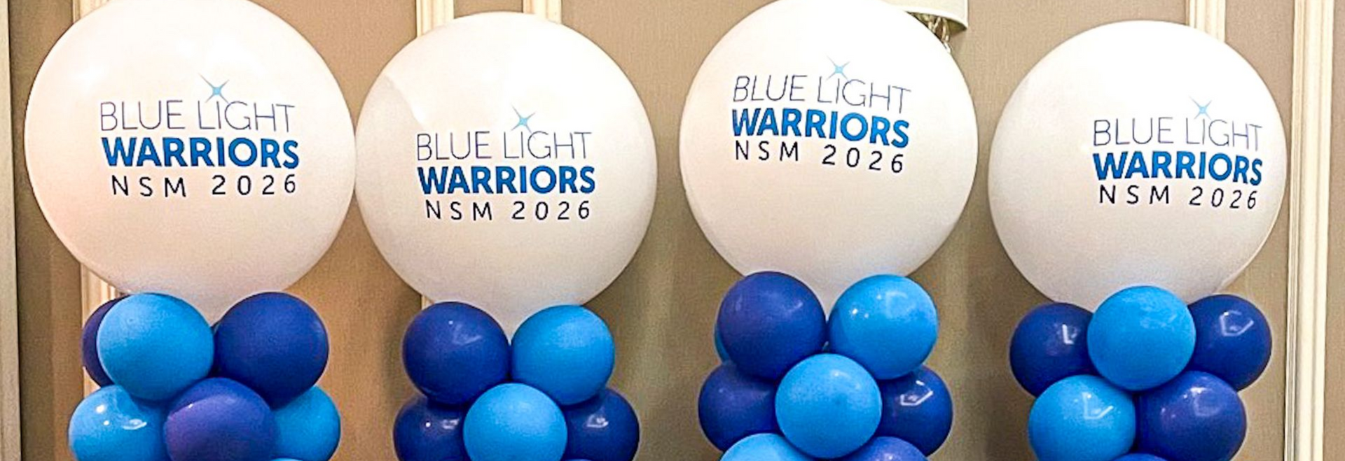 Four white balloons with blue lettering above clusters of blue balloons. 