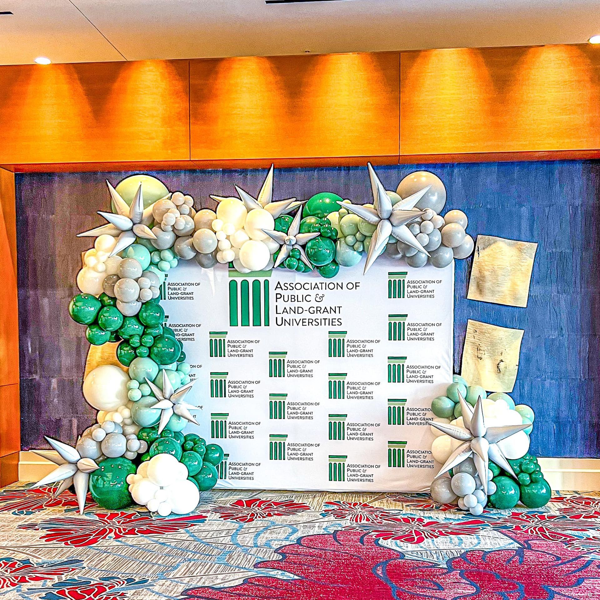A wall decorated with green and white balloons in a room.