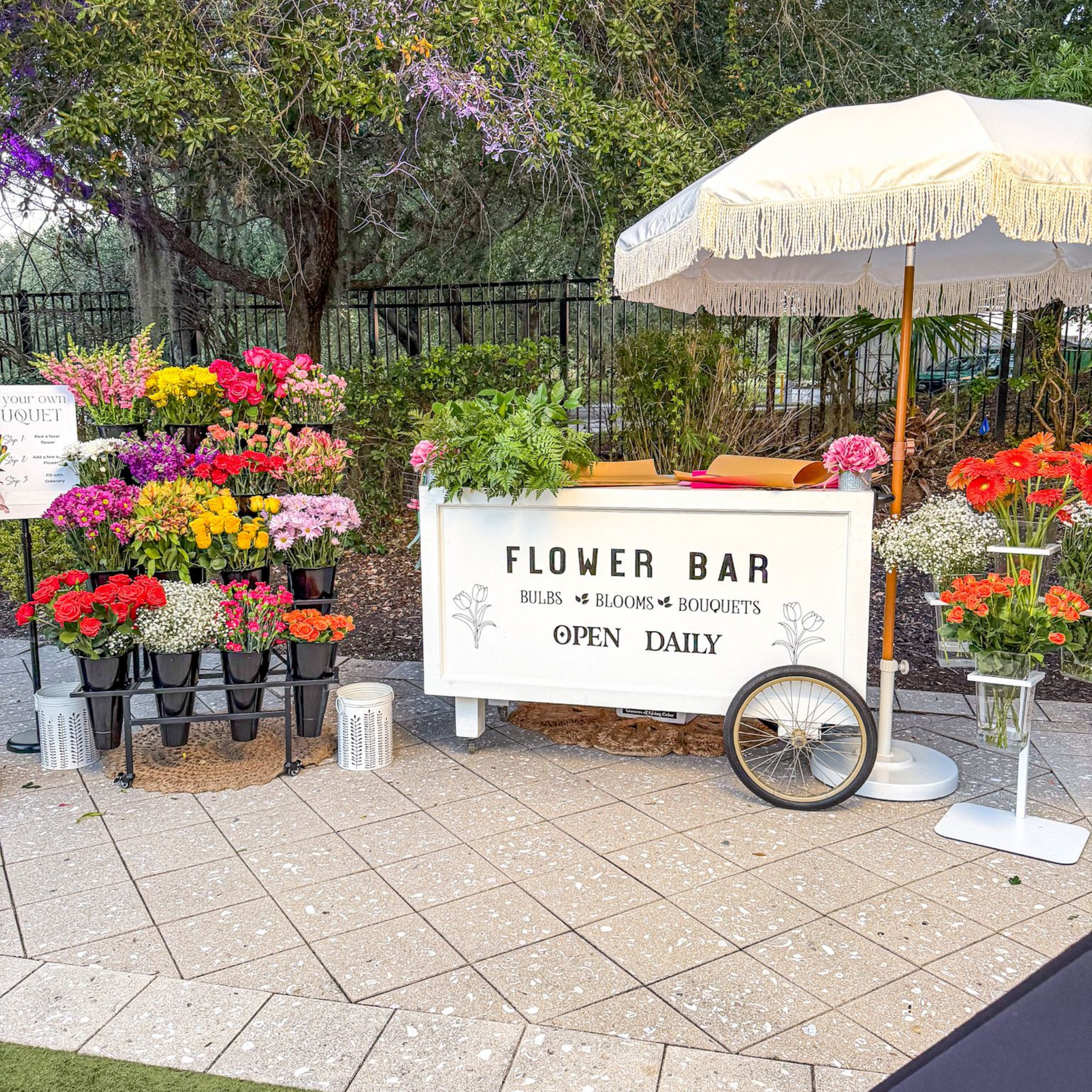 A room filled with flowers and a cart that says flower bar