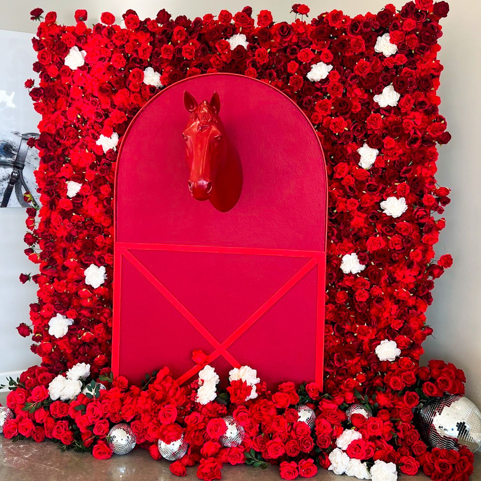Red floral wall with a bright pink arched door and horse head decoration.