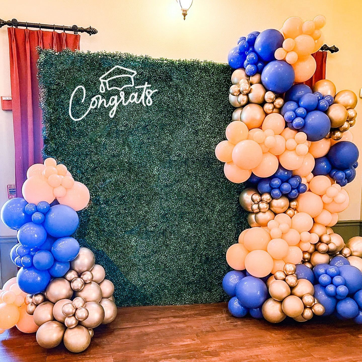 A wall covered in balloons and a sign that says `` congratulations ''.