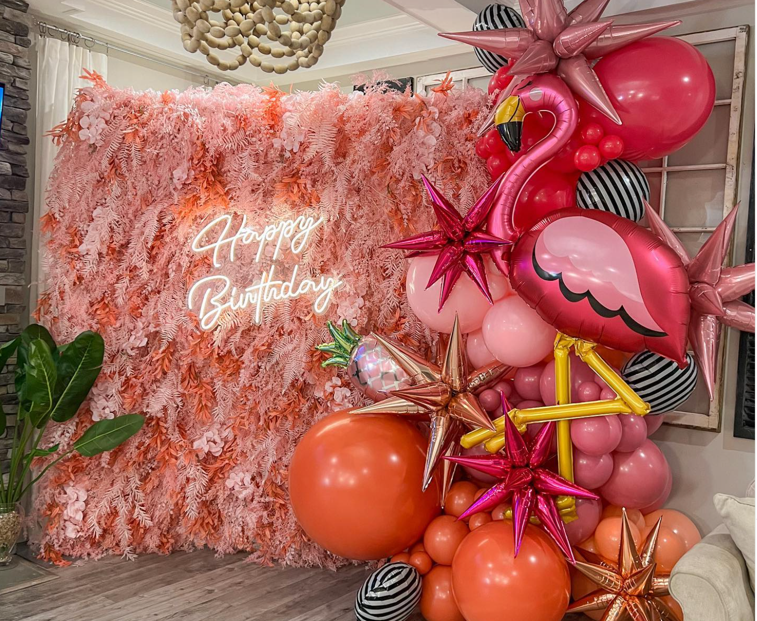 a room filled with balloons and a neon sign that says `` happy birthday '' .