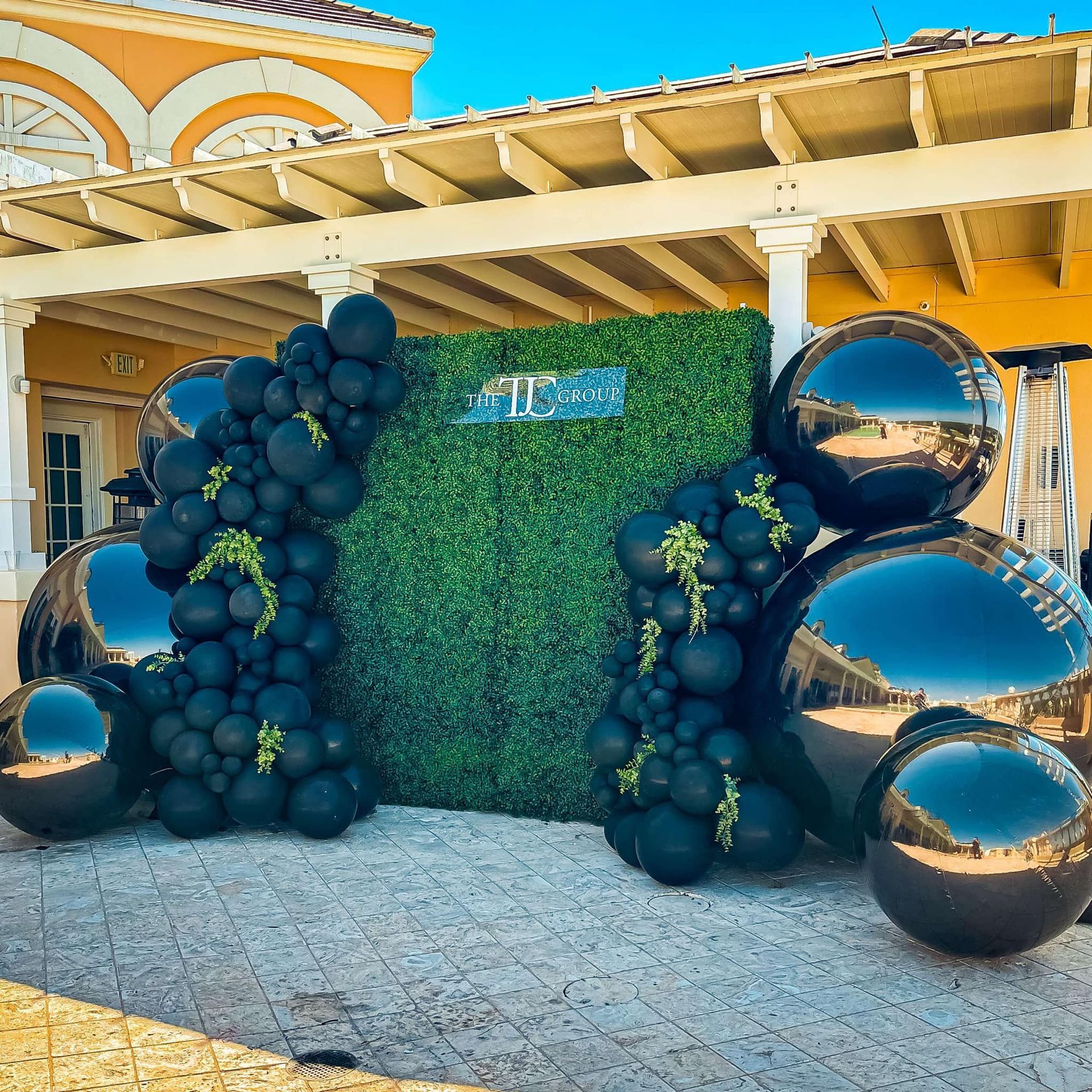 A bunch of black balloons are sitting in front of a building.