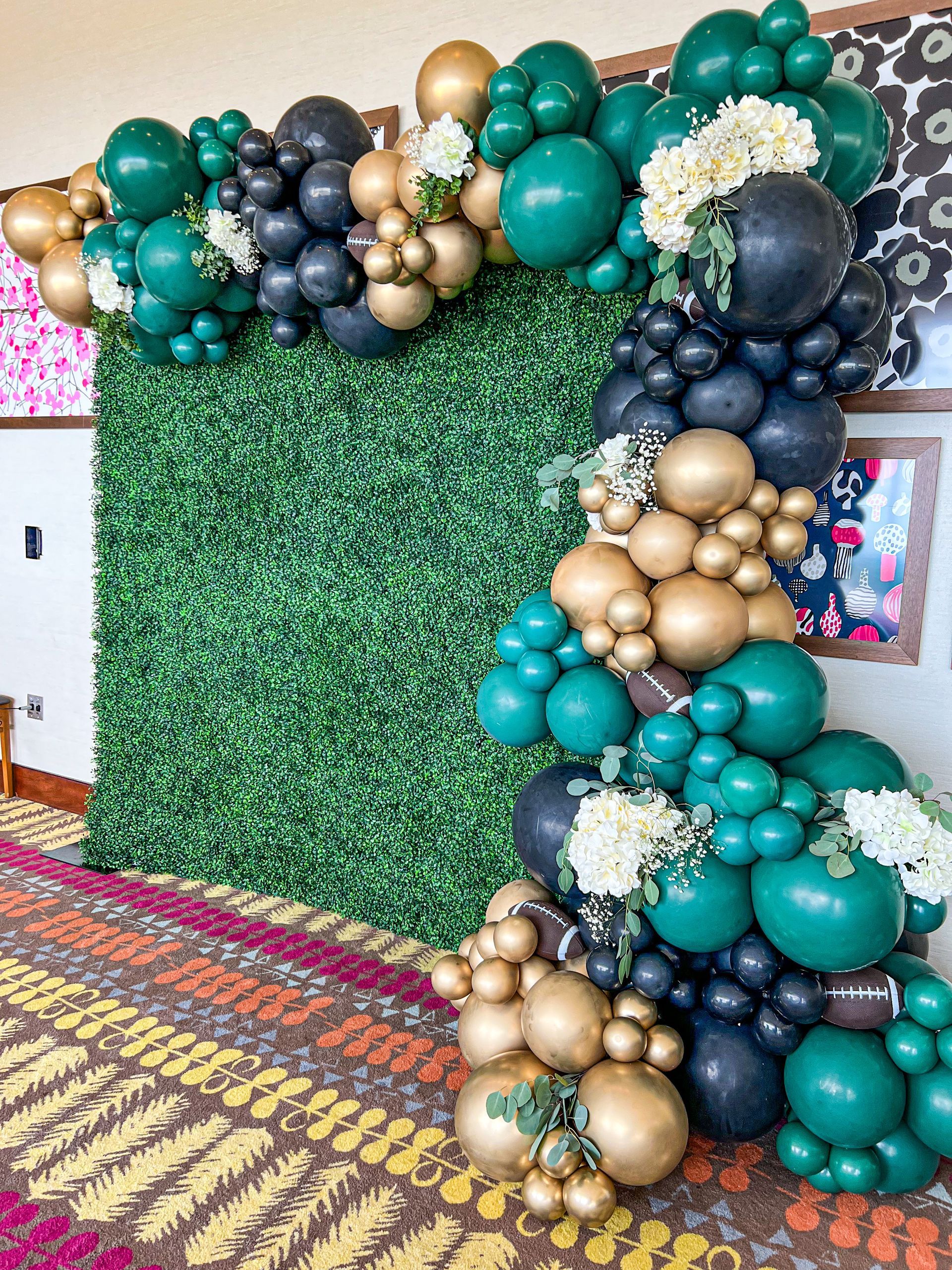 a bunch of balloons are sitting in front of a green wall .