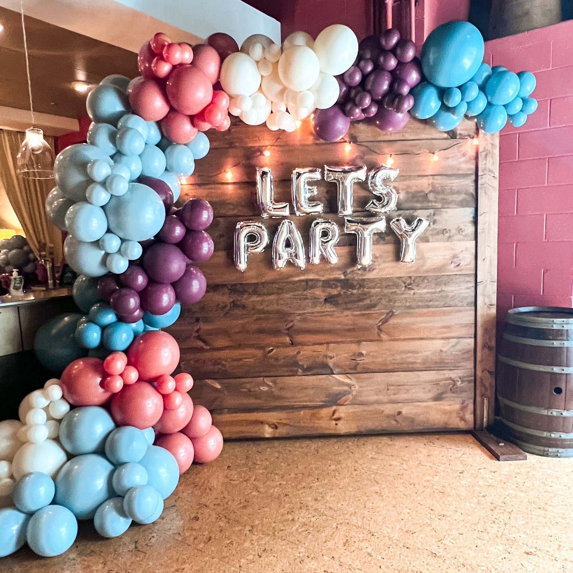 A wooden wall with balloons and a sign that says let 's party