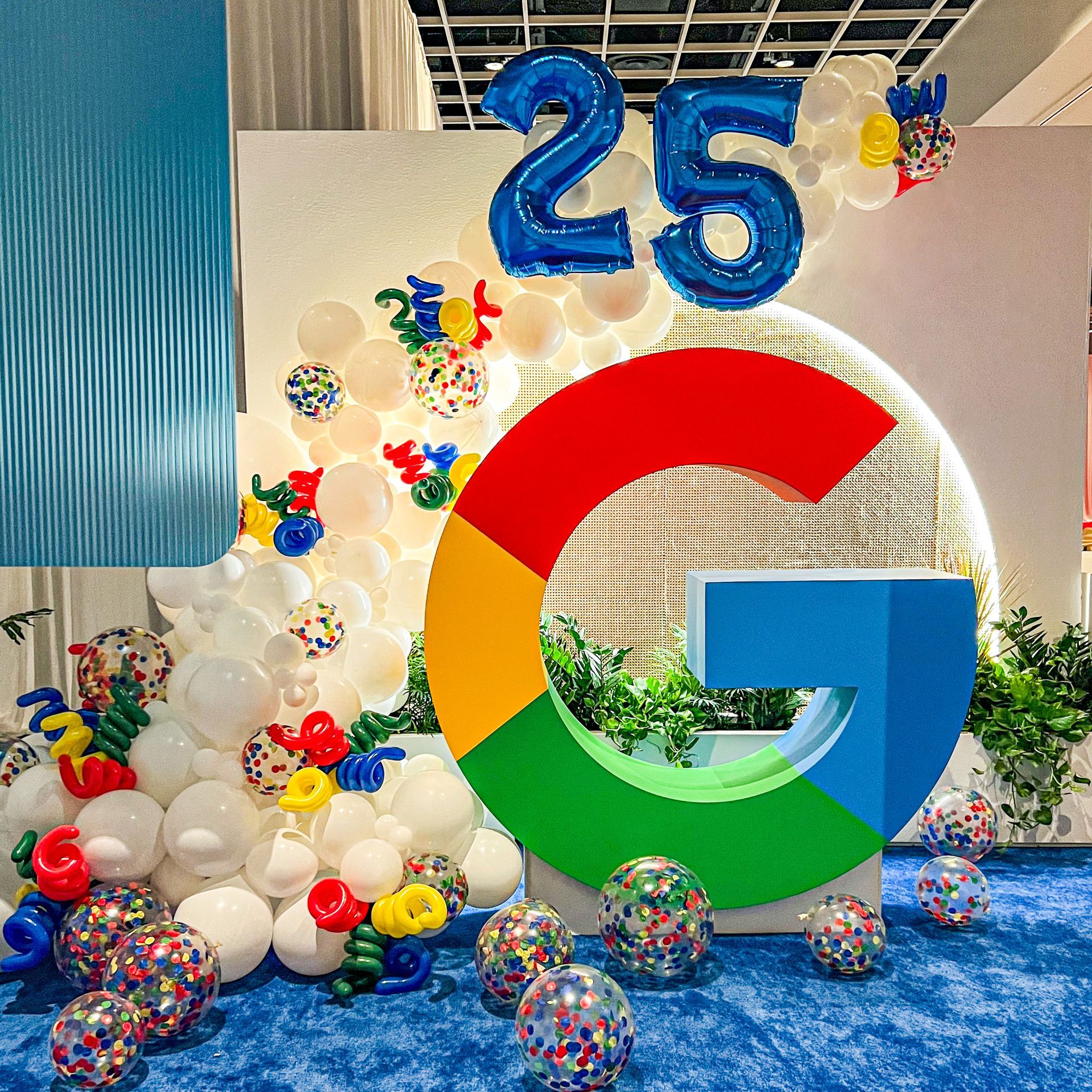 a large g is surrounded by balloons and confetti .