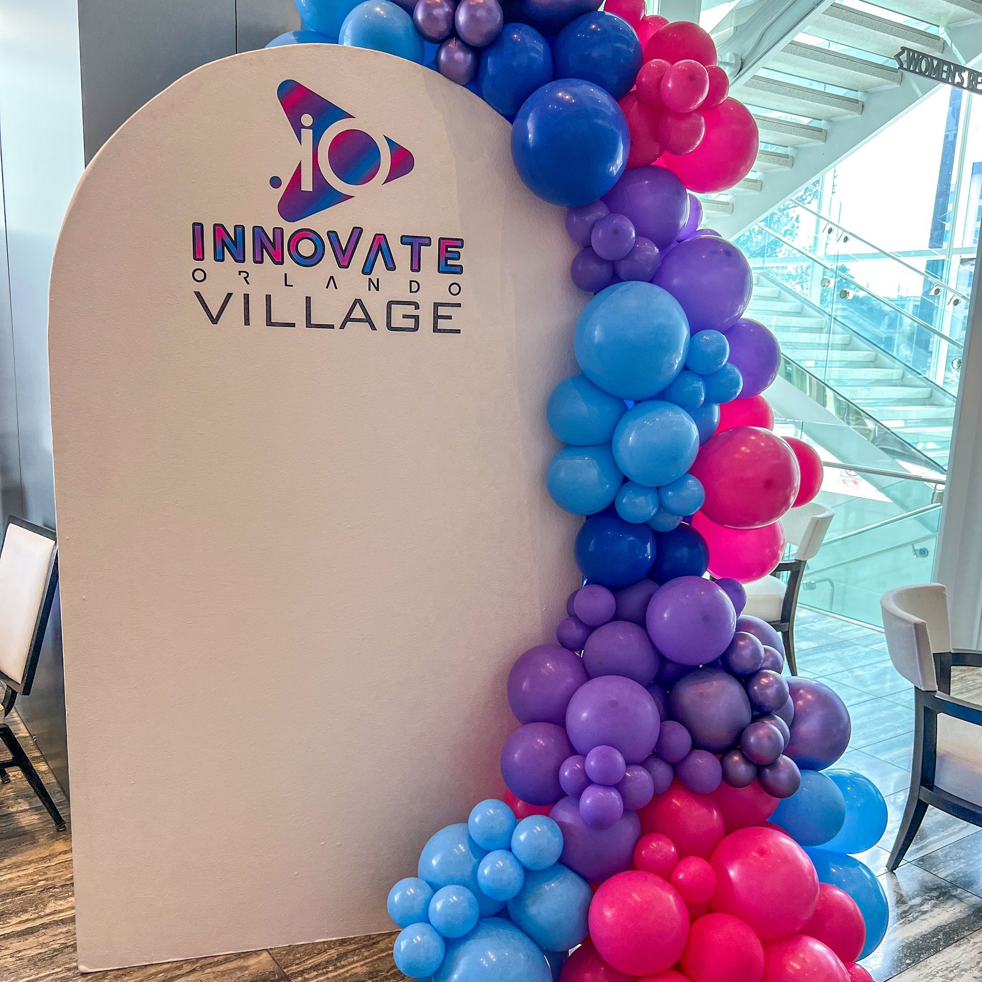 a sign that says innovate village is surrounded by balloons .
