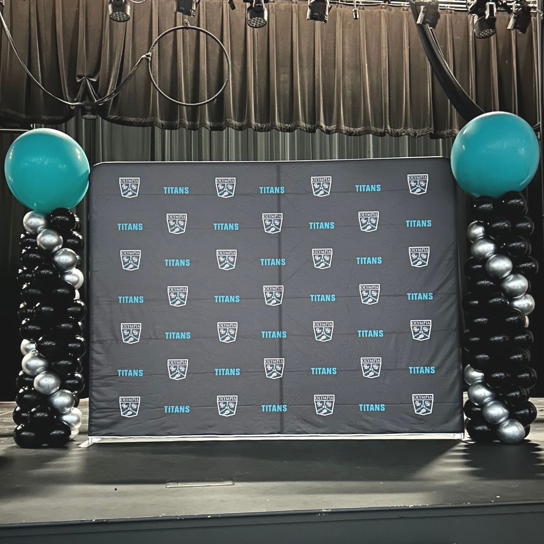 A stage with a backdrop and balloons on it