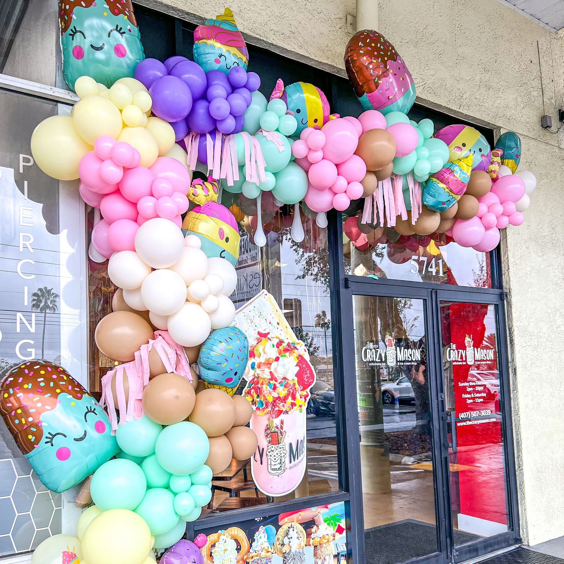 A store front with balloons and a sign that says ' piercing ' on it