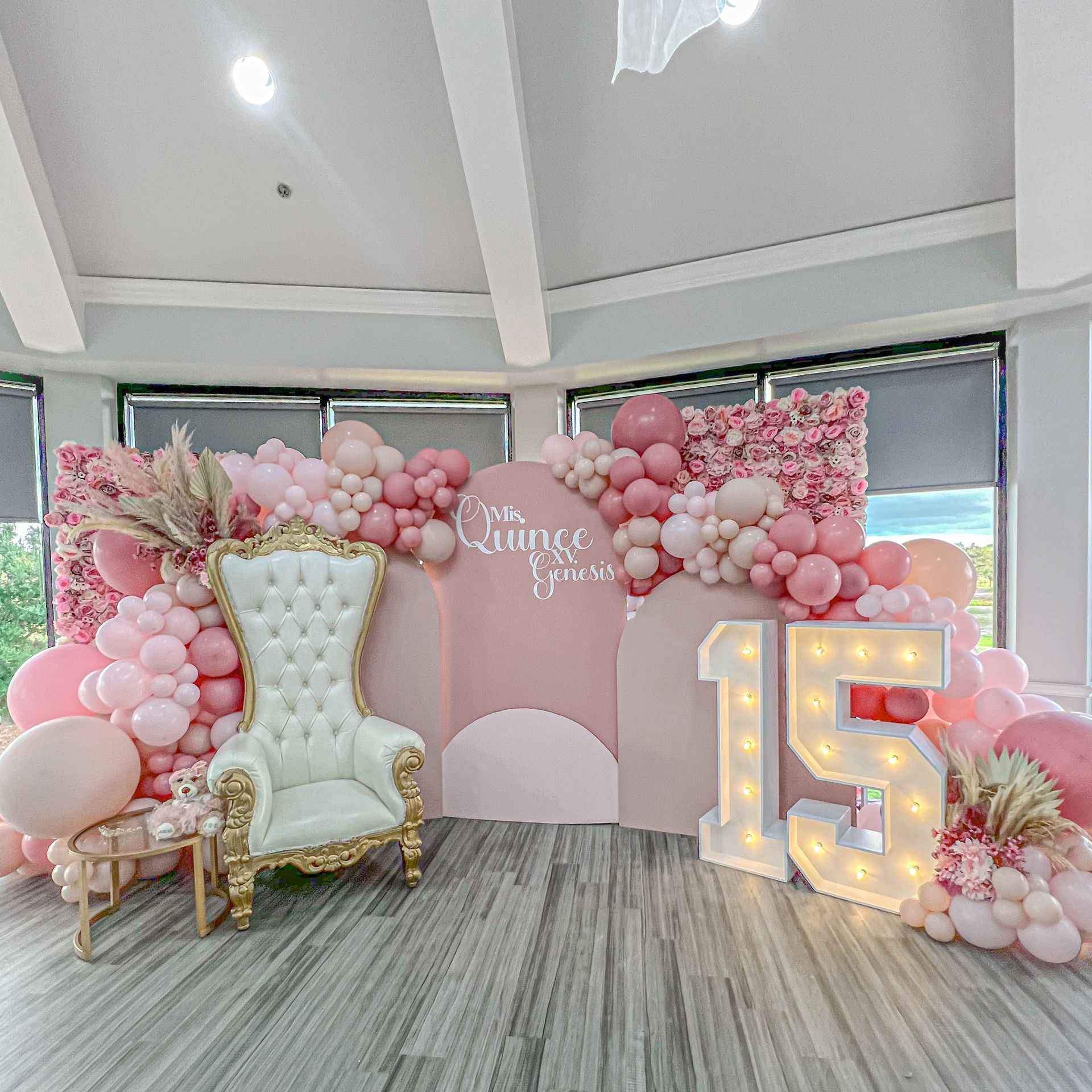 A room decorated with pink balloons and a chair.