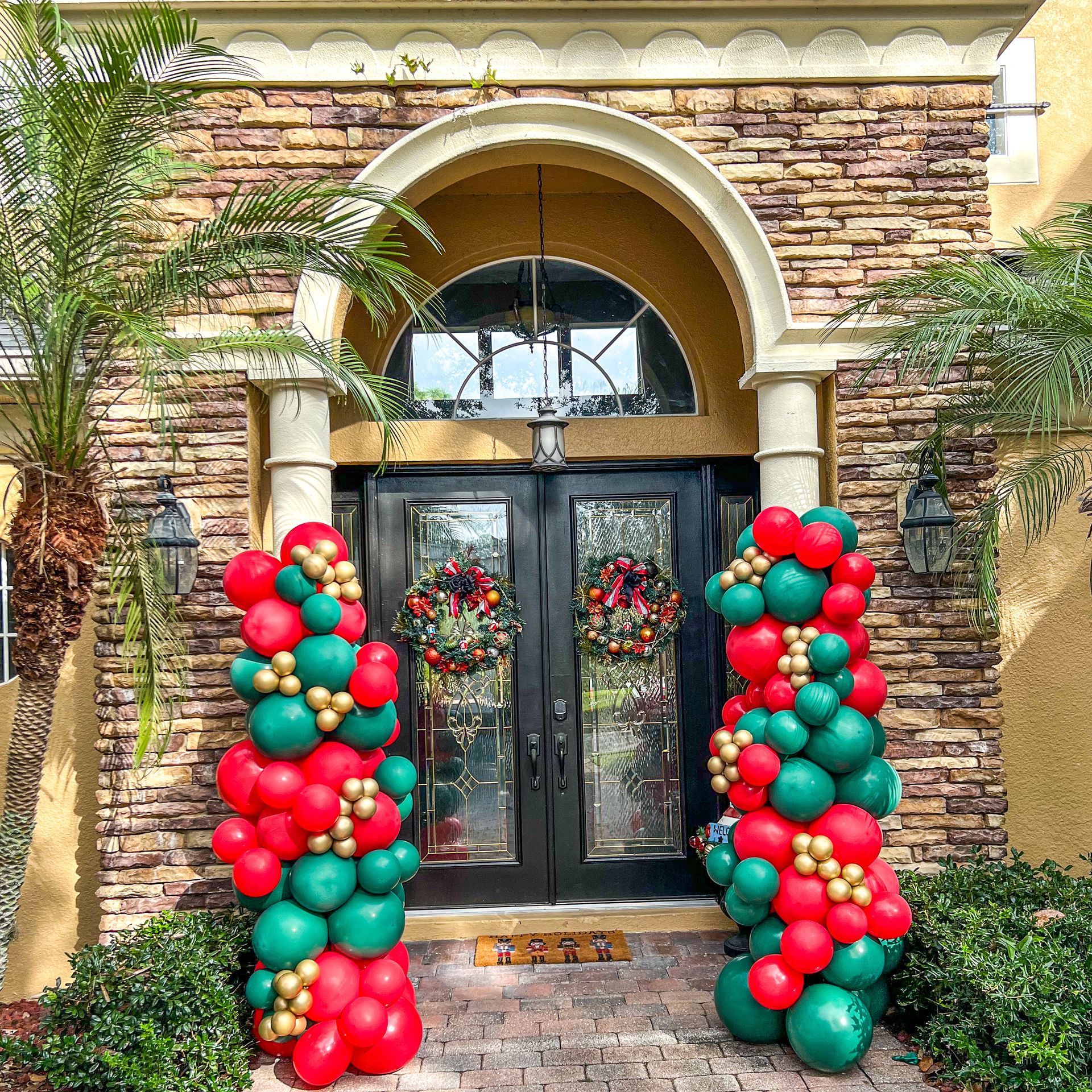 The front door of a house is decorated with red , green and gold balloons.
