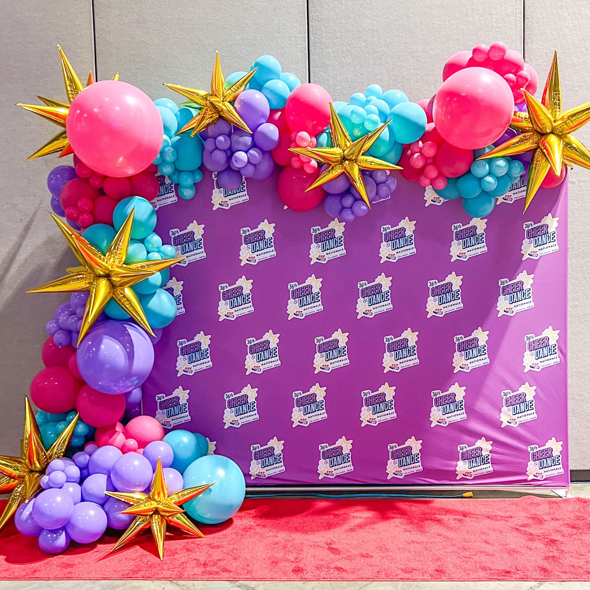 A purple backdrop with balloons and stars on it