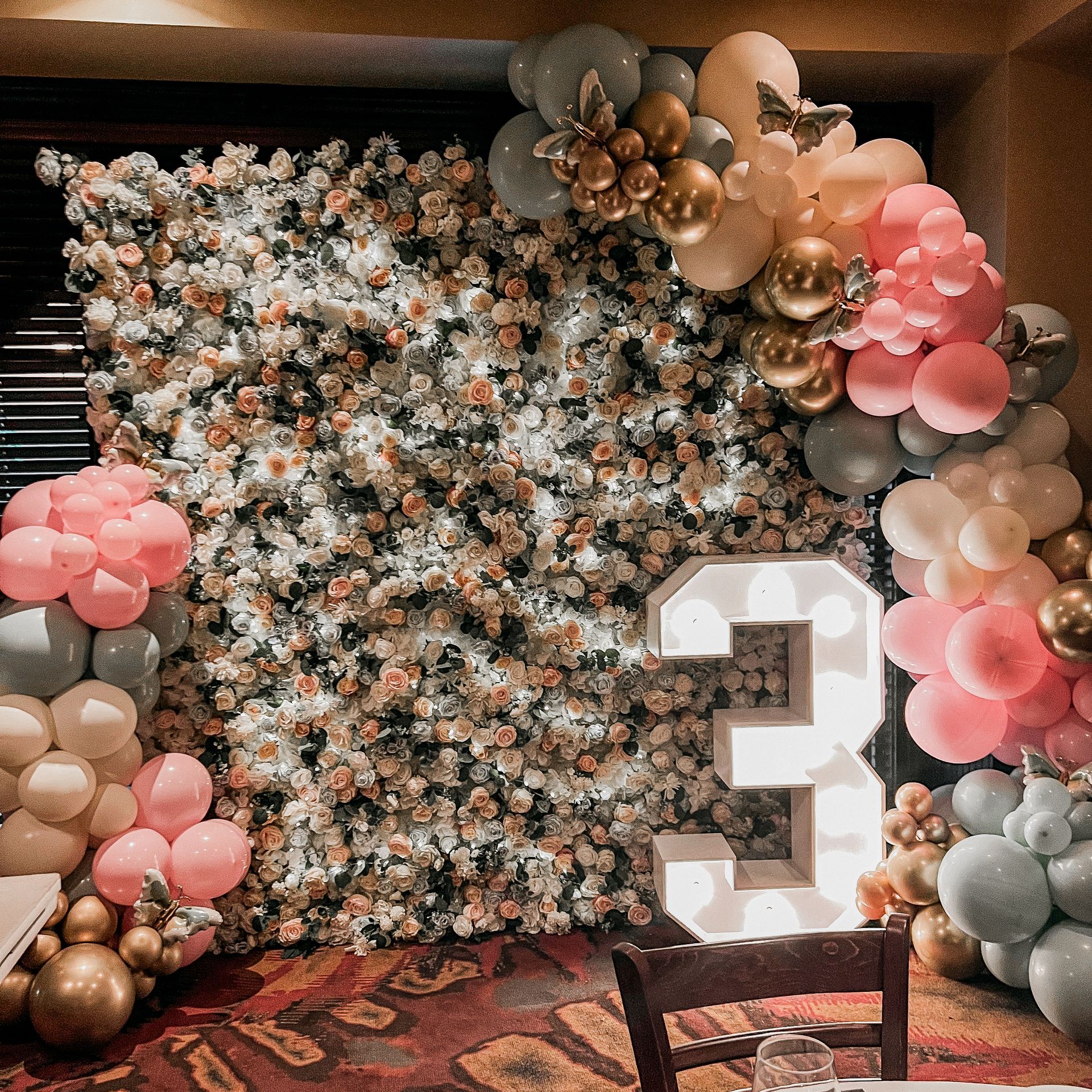 A large number 3 is surrounded by balloons and flowers