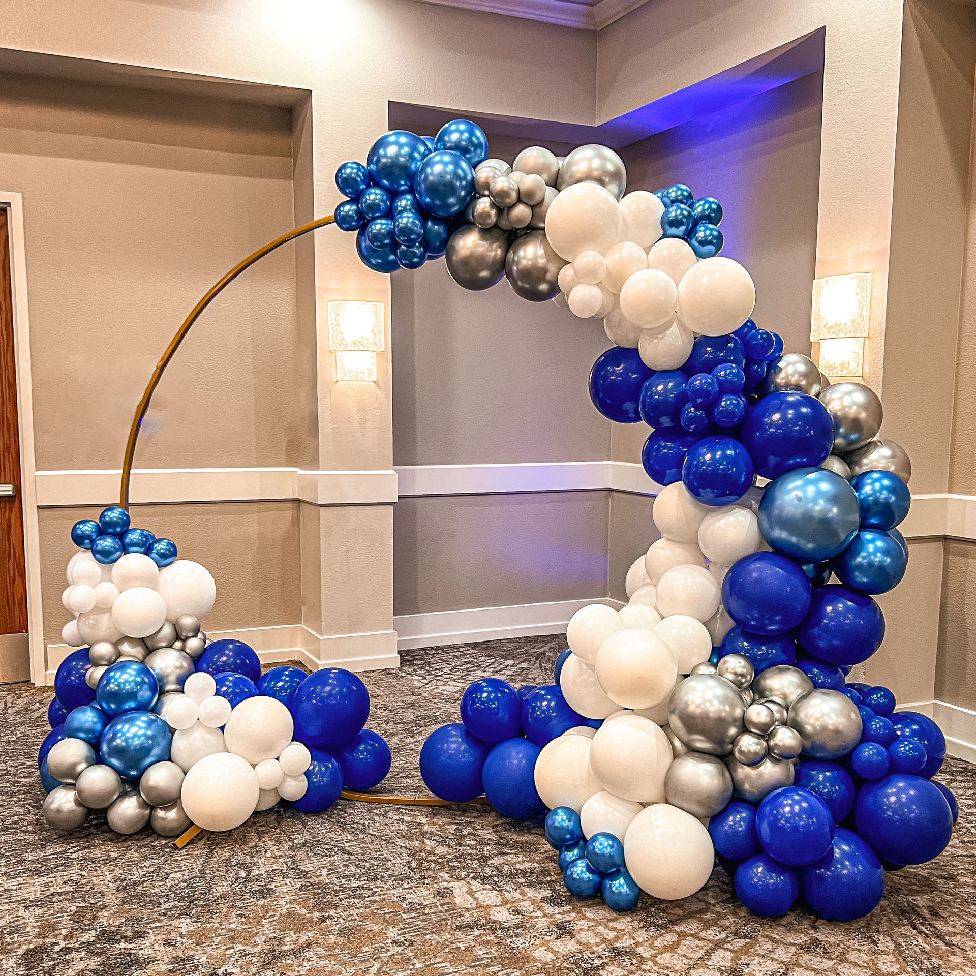 a room filled with blue , white , and silver balloons .