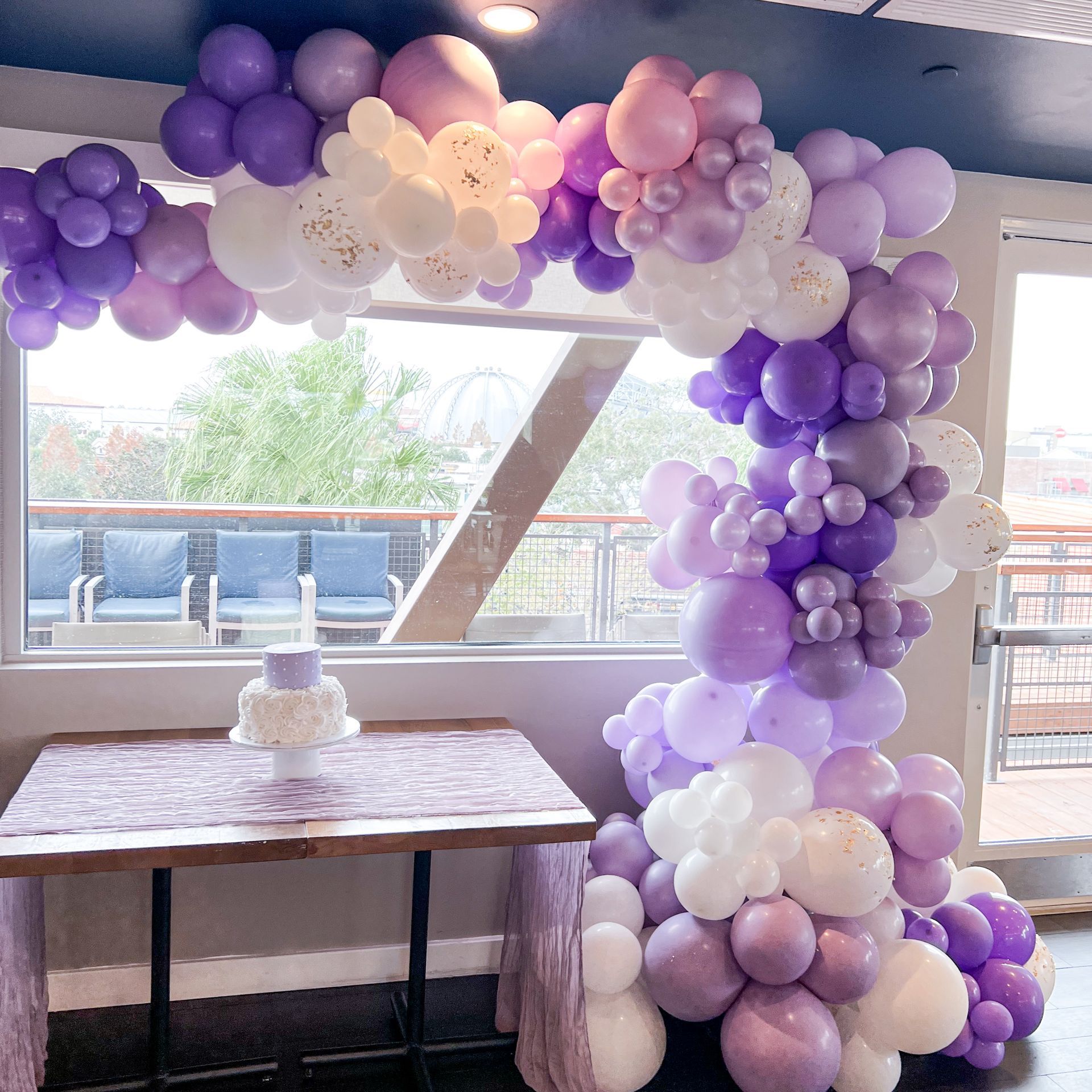 A table with purple and white balloons on it