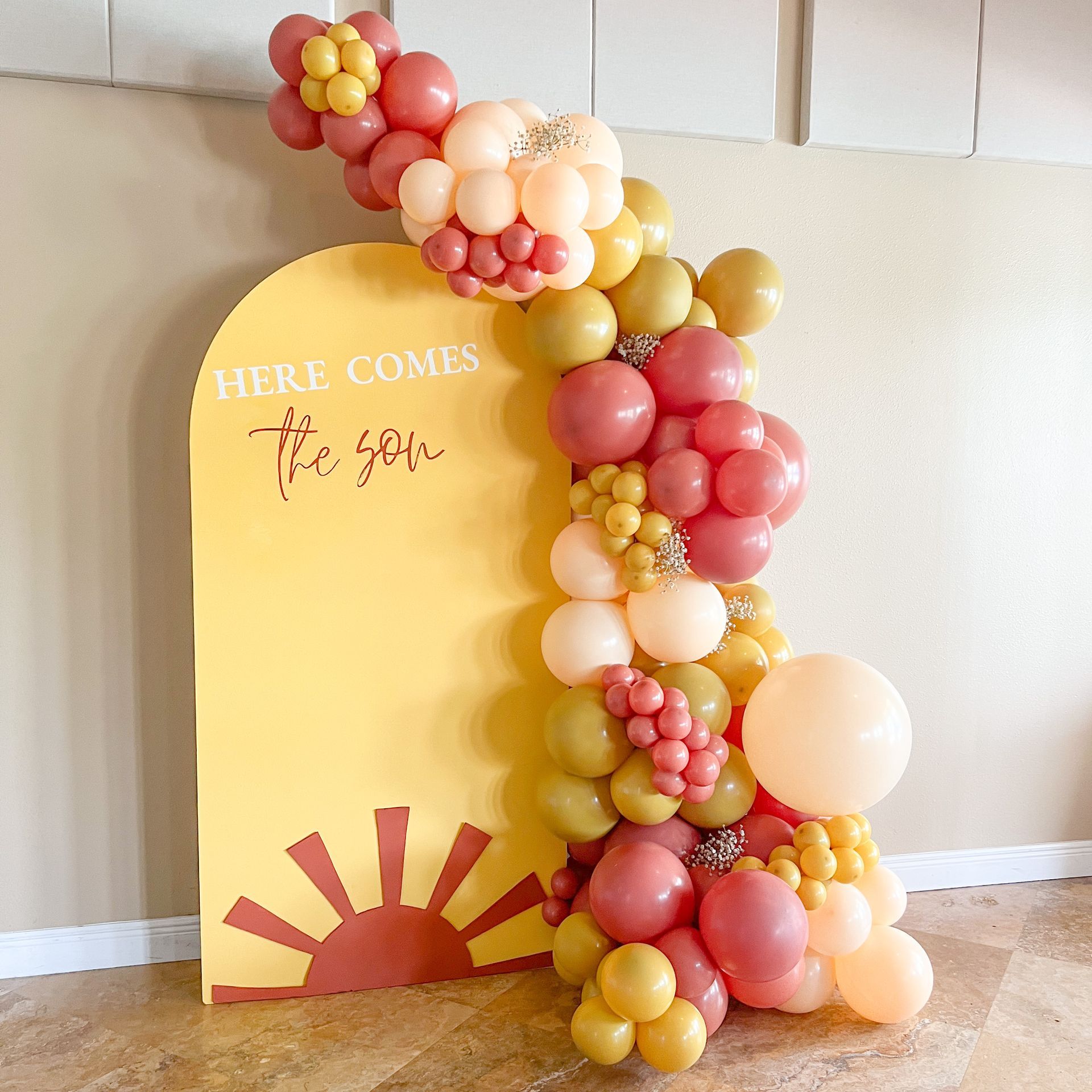 a sign that says here comes the sun is surrounded by balloons