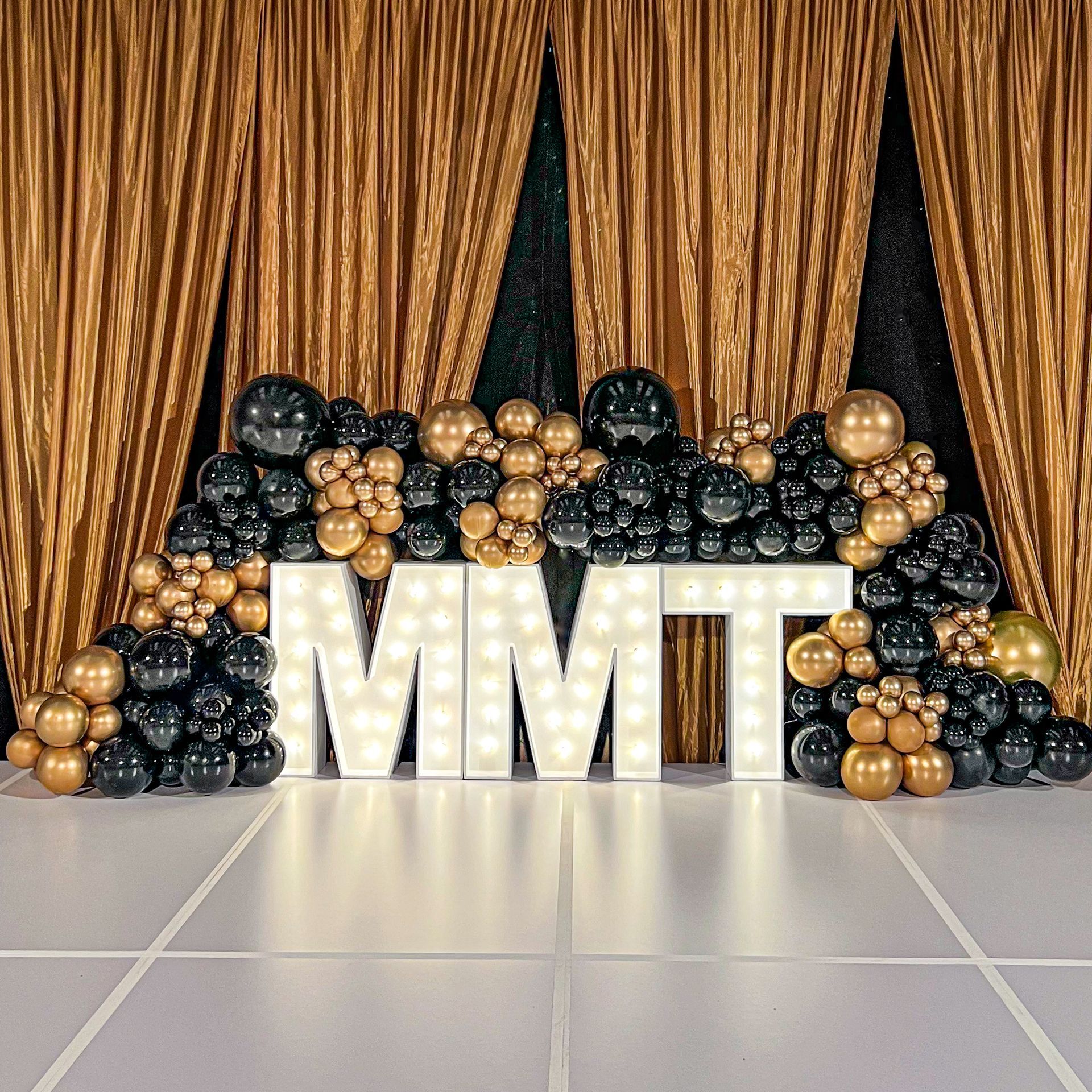 The word mmt is surrounded by balloons and lights