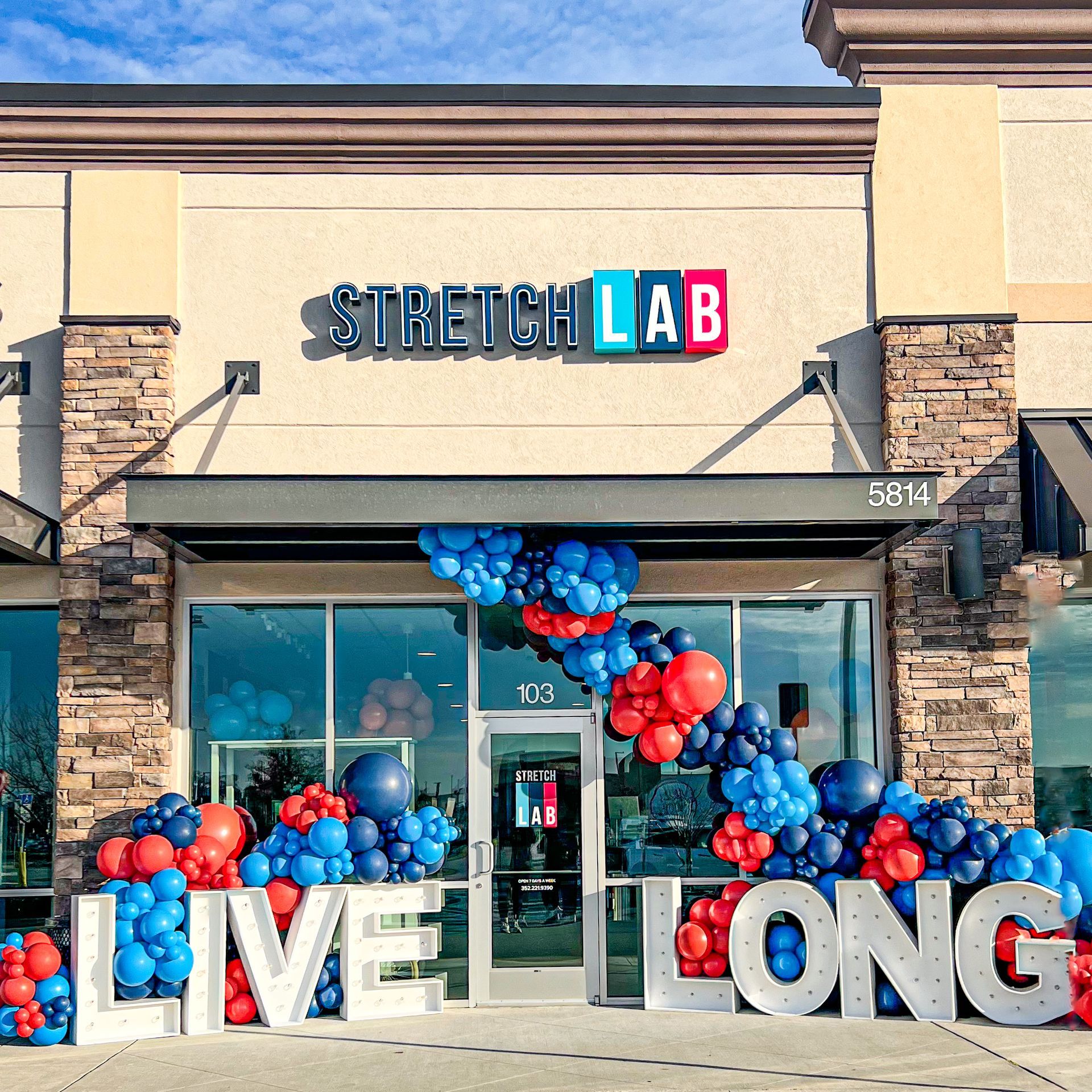 A stretch lab store is decorated with balloons and letters that say live long