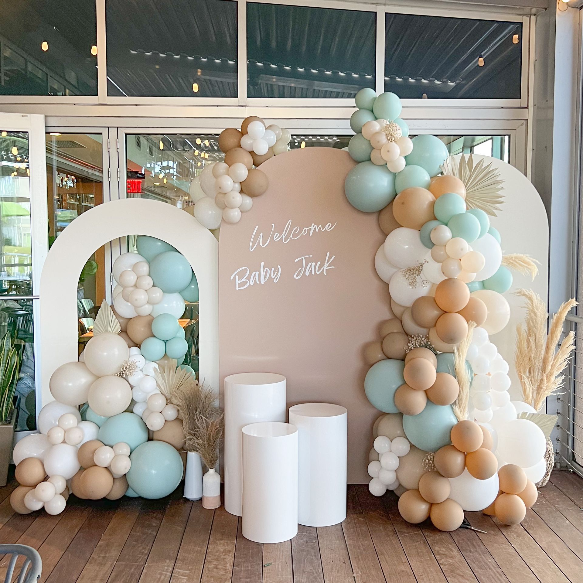 A wall decorated with balloons and a sign that says welcome baby jack