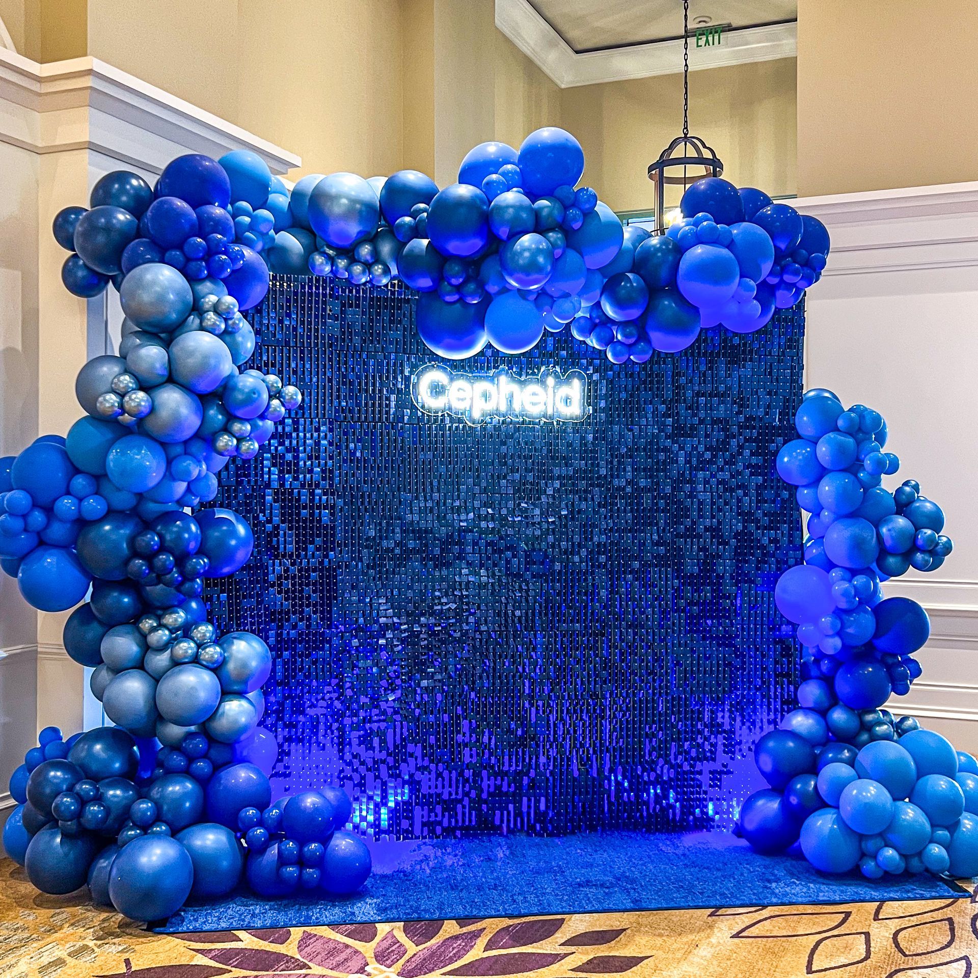 A wall covered in blue balloons and a sign that says cephalo.
