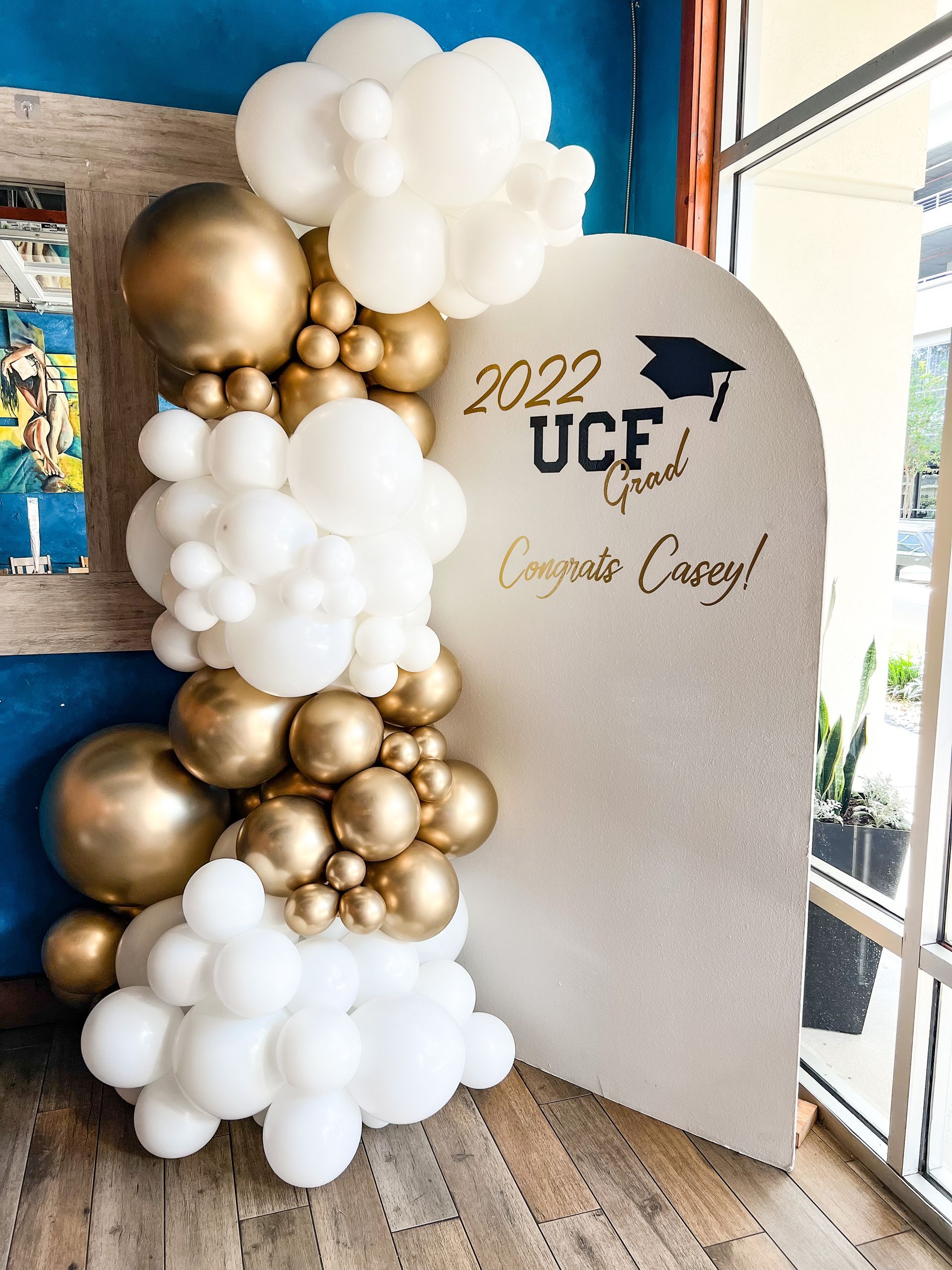 A wall with balloons and a graduation cap on it.